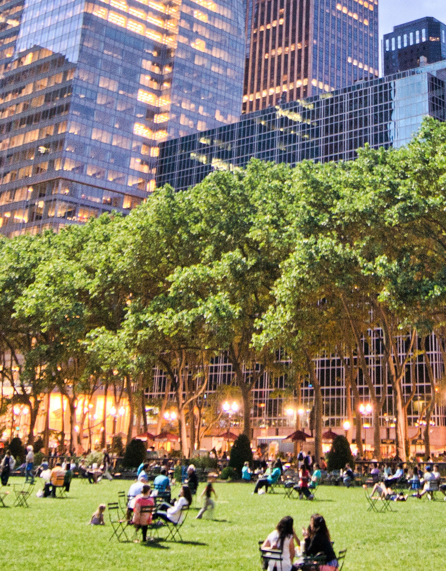 Bryant Park - people relaxing and walking about grass with tall buildings in background