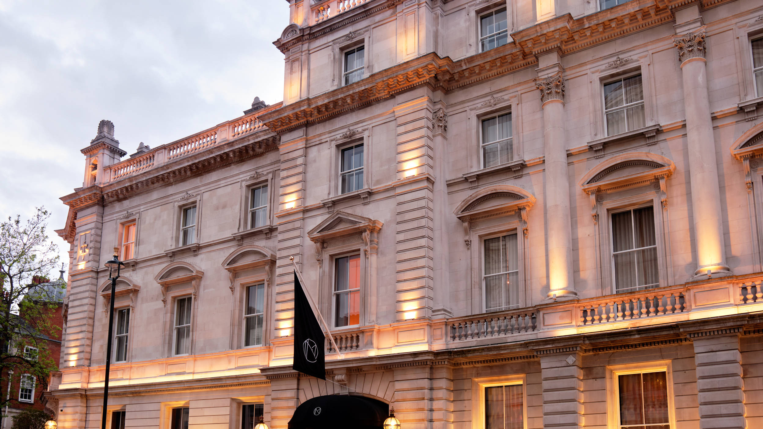Hotel exterior with historic building with ornate architecture, lit up at dusk.