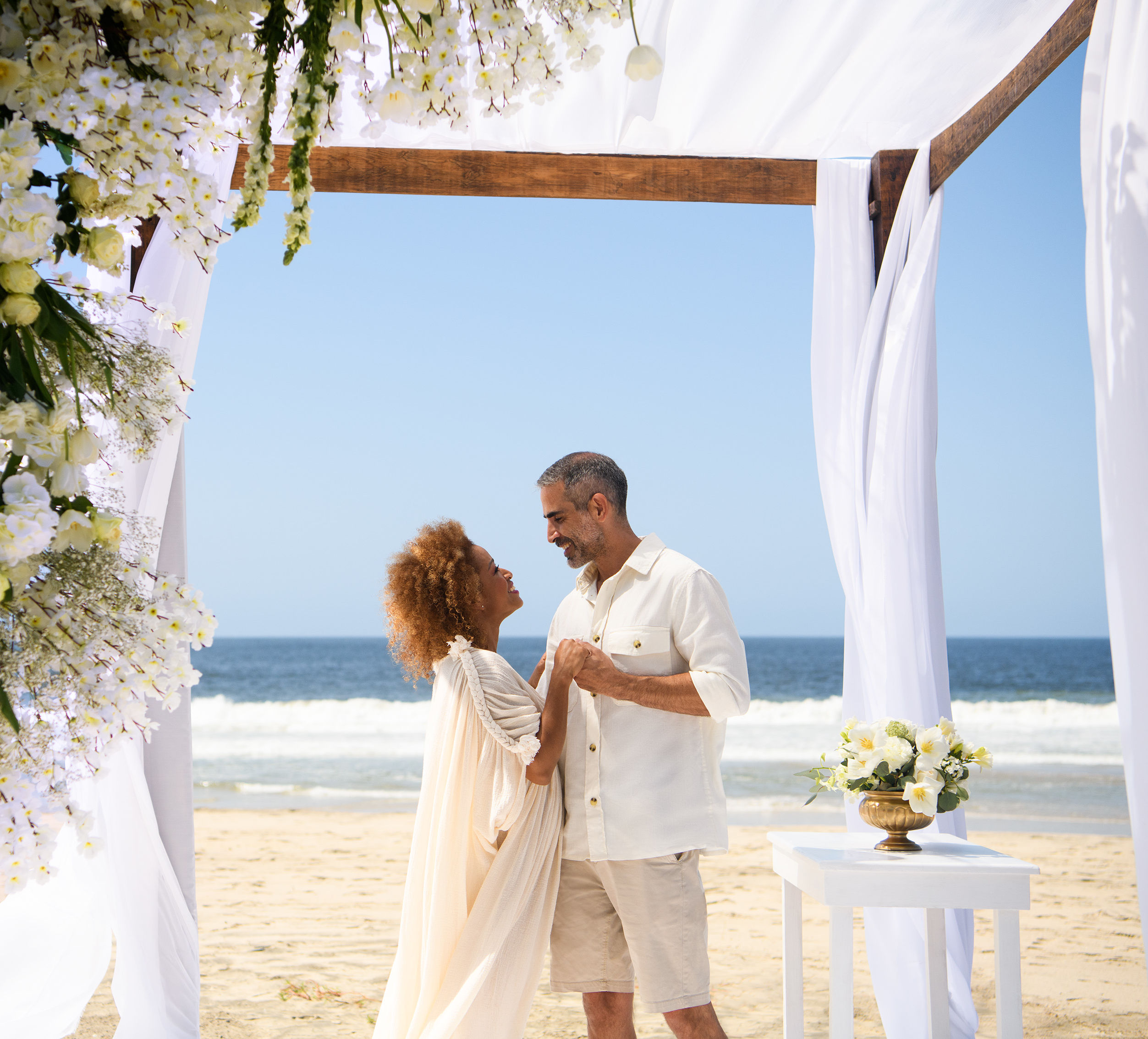 Un couple se mariant sous une treillis en bois sur la plage.