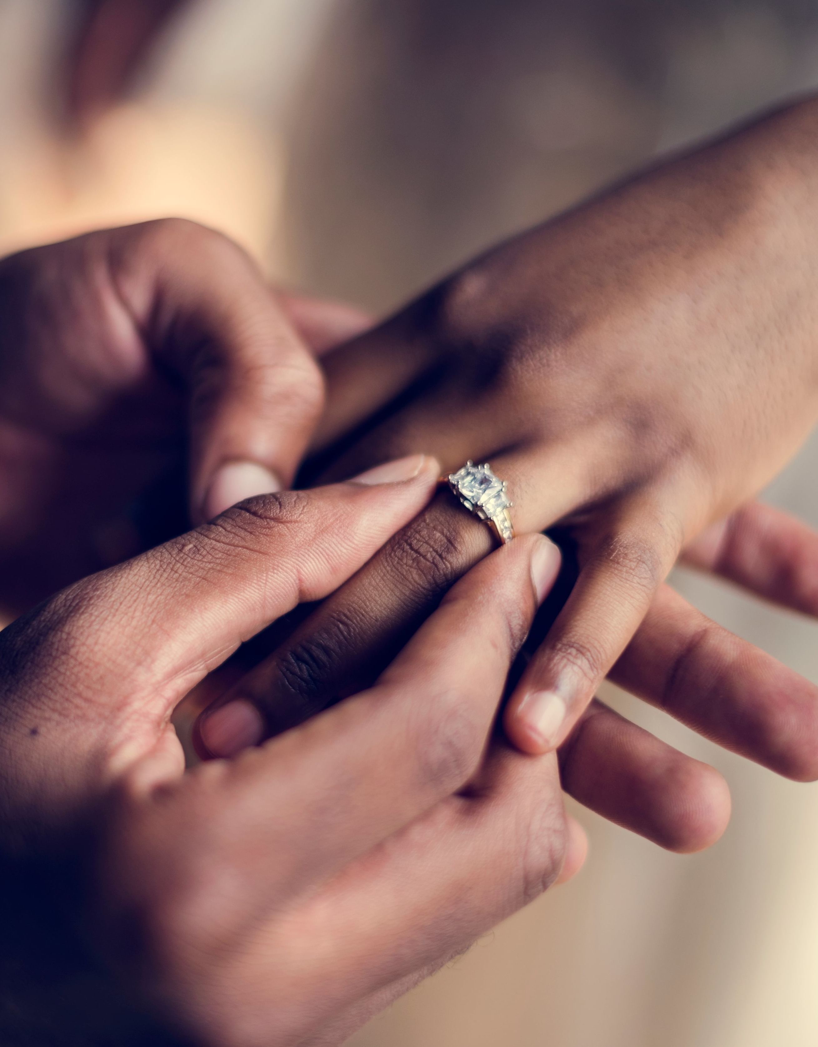 Primer plano de un hombre colocando un anillo en el dedo de una mujer