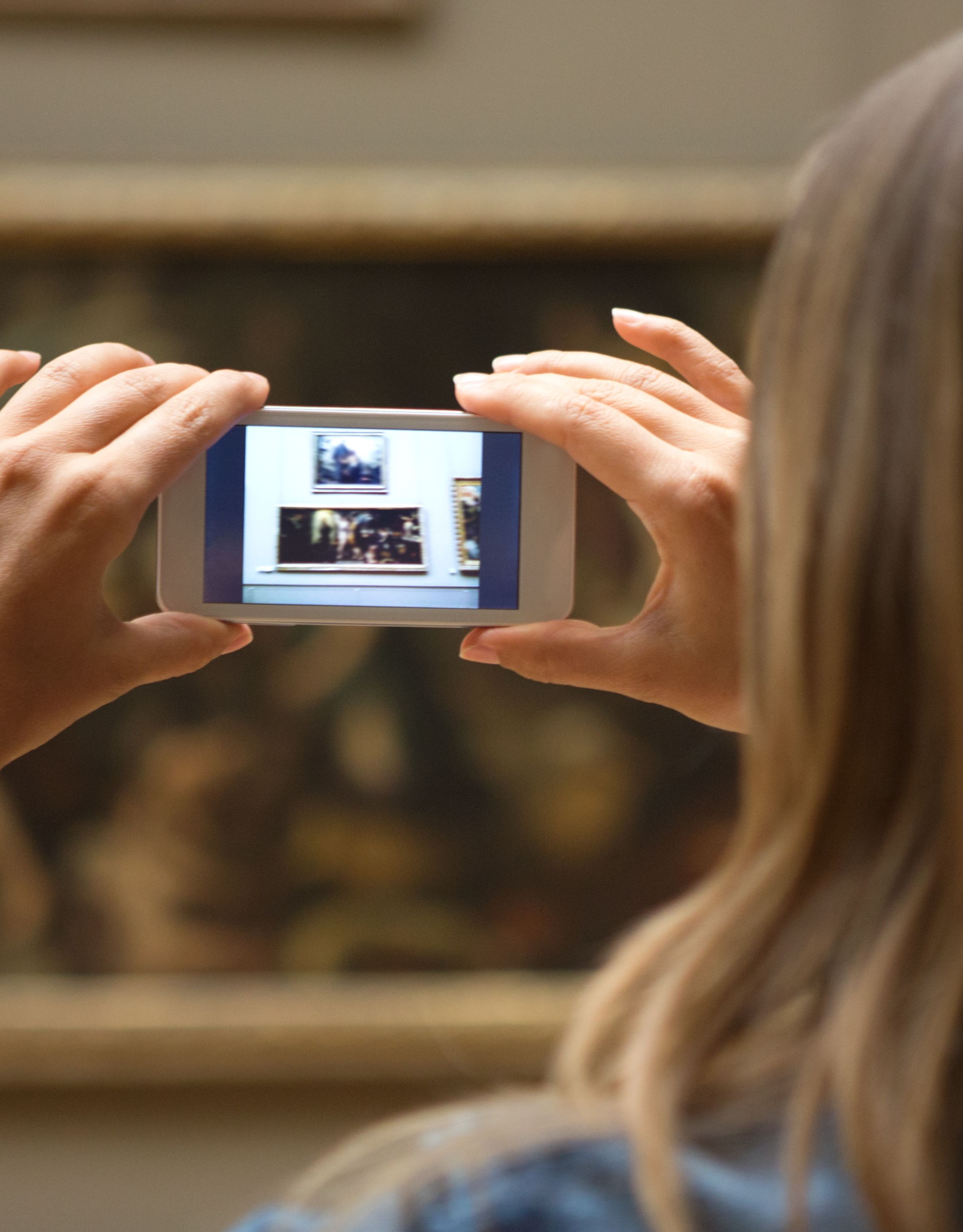 Woman taking a picture of a painting in an art gallery or museum
