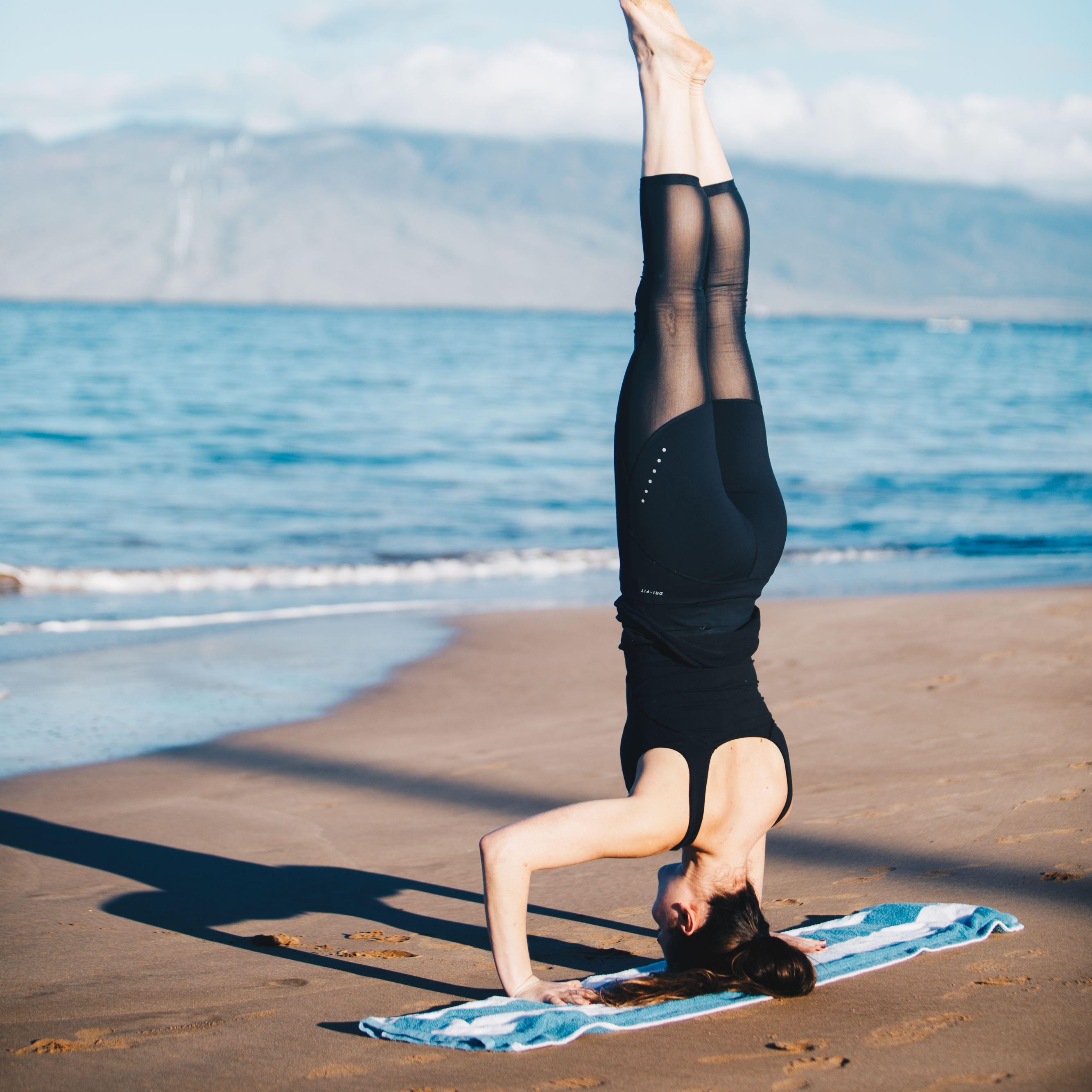 Woman doing a headstand on the beach