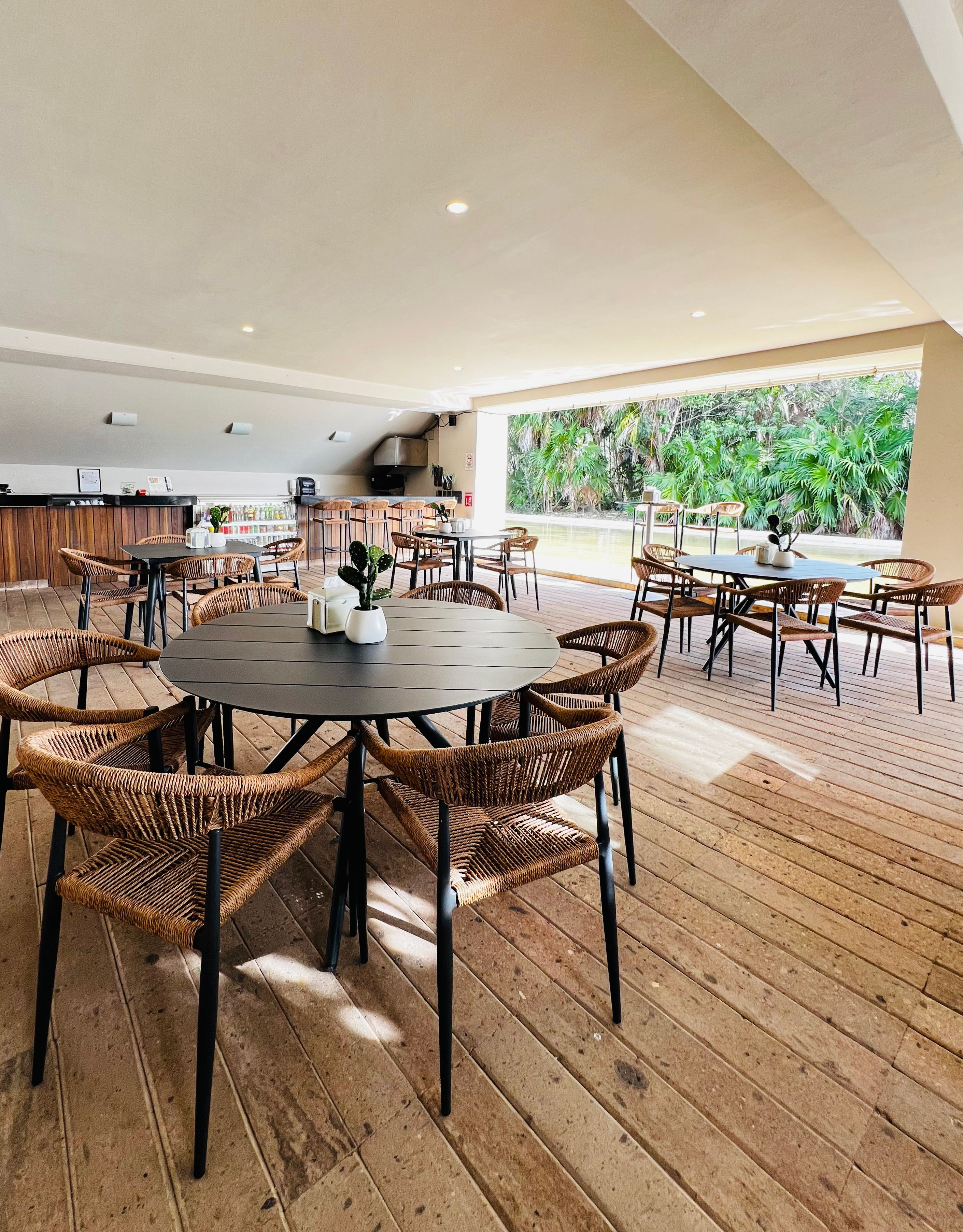 Restaurant-Tablet mit Weidenstühlen und Aufnahme des Baumbereichs im Freien