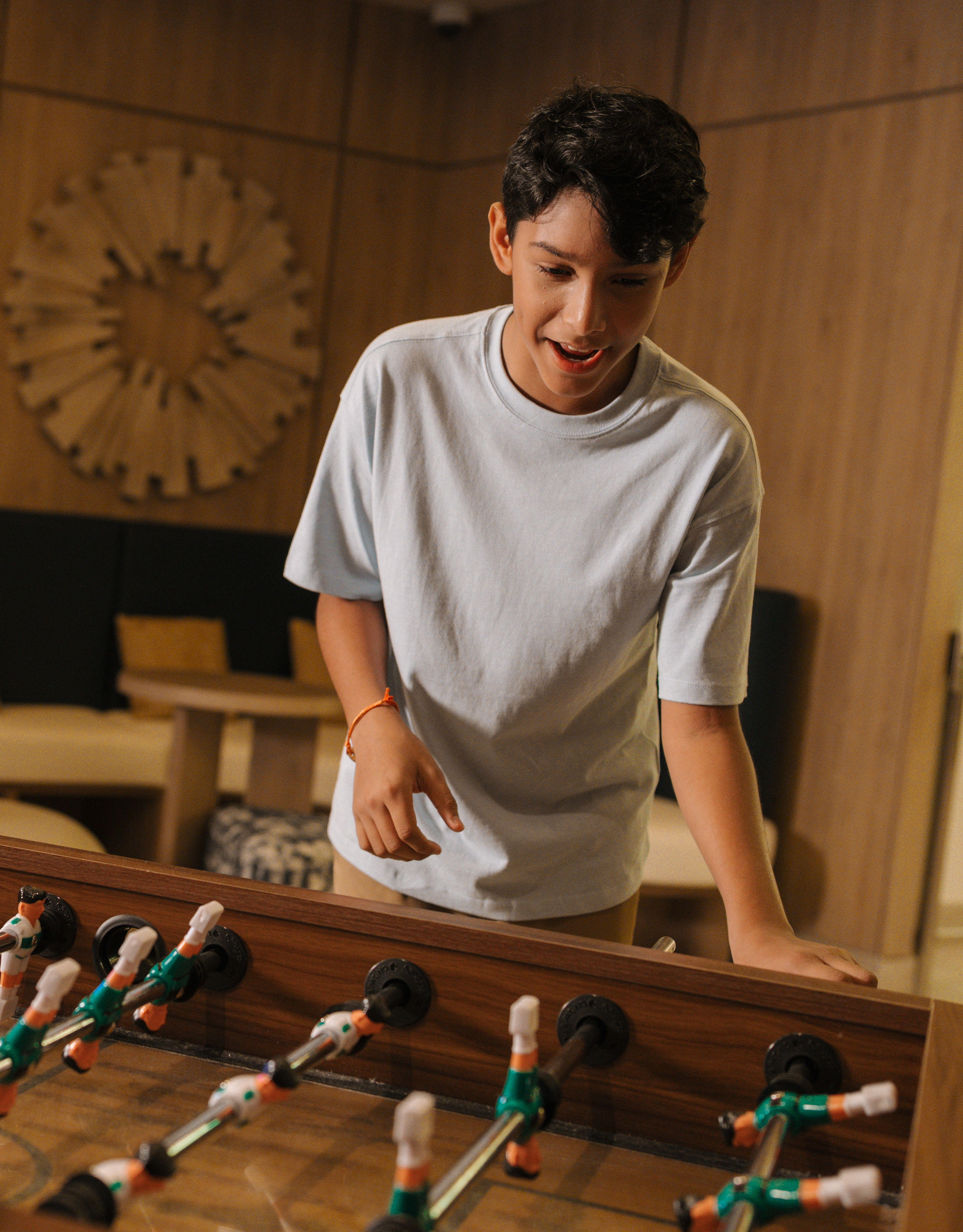 Boy smiling as he plays table football in white shirt