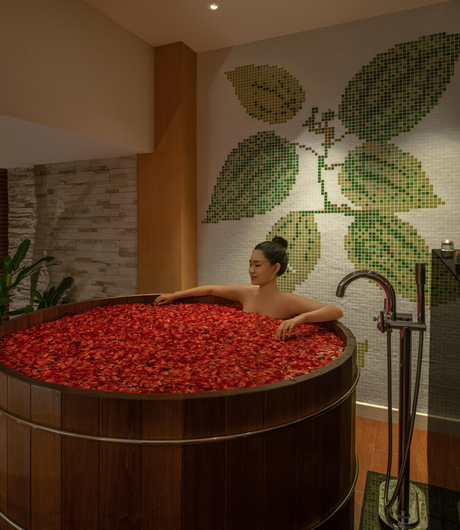 スパで癒しの赤い花びらを片手にお風呂を楽しむ女性