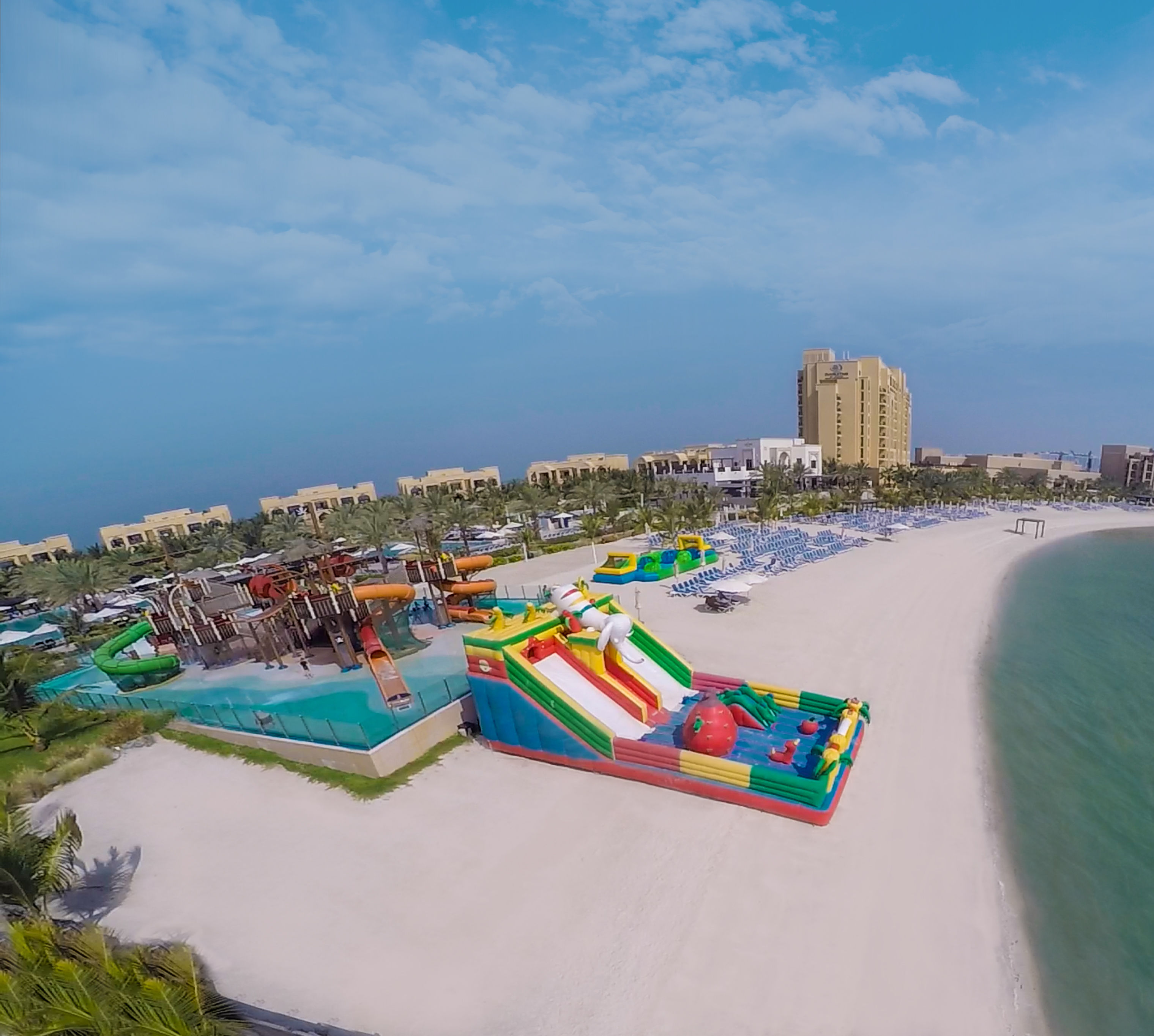 Aerial view of the beach adjacent to the hotel's waterpark, and bounce castle.