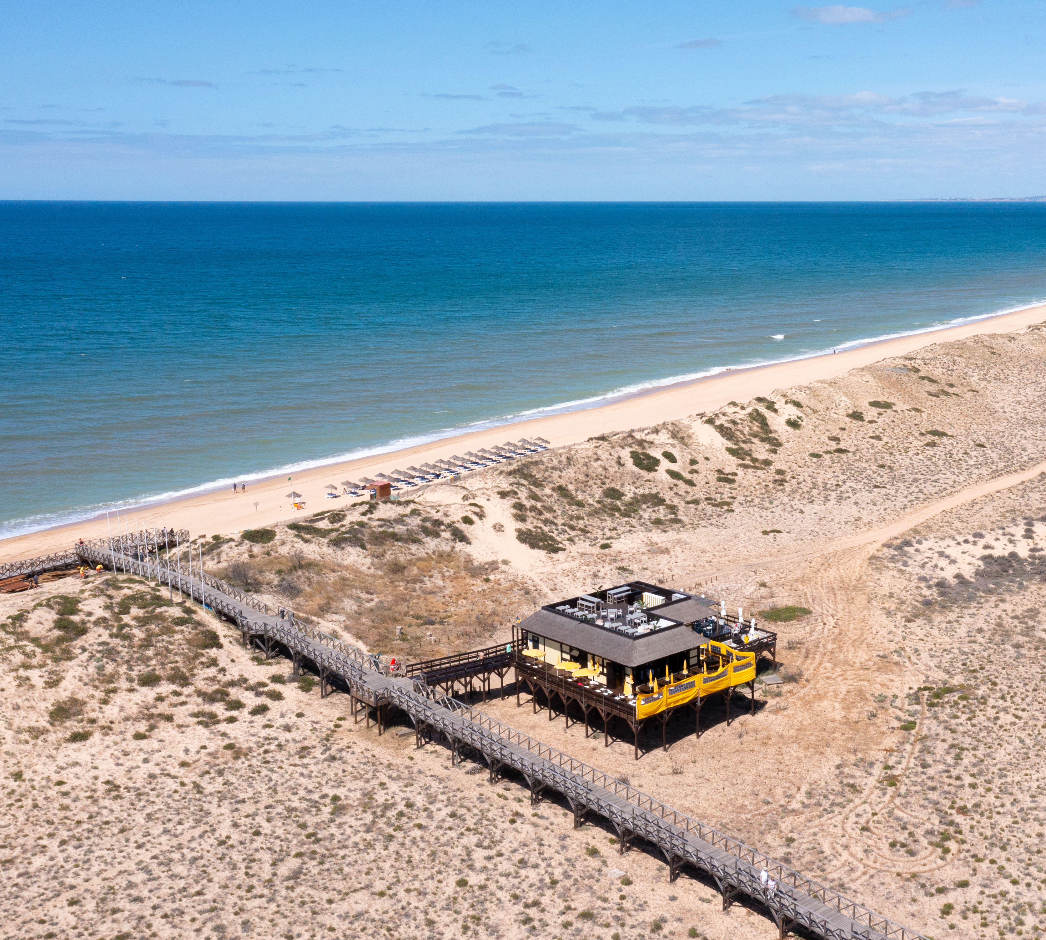 Aerial view of a yellow concession stand on a sandy beach 