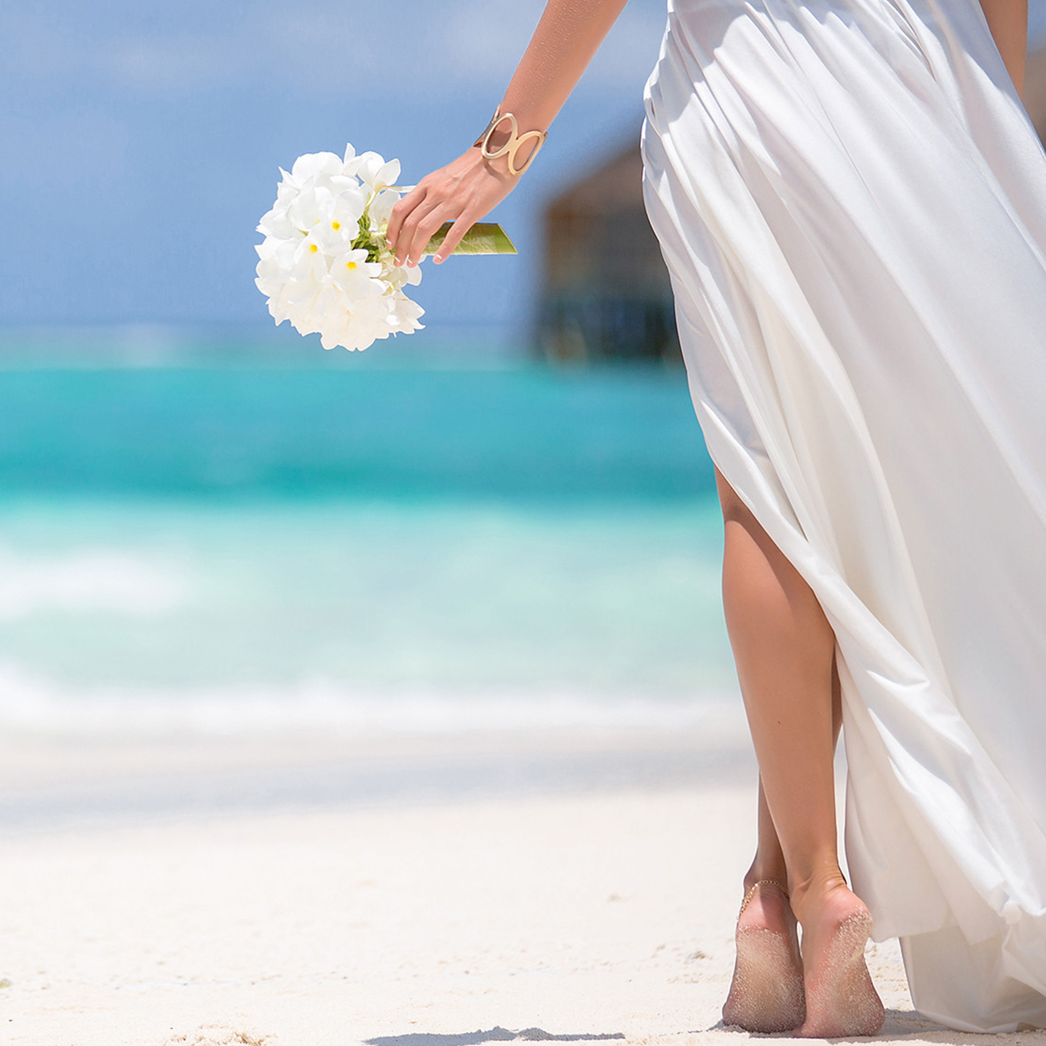 Bride with bouquet walking along beach