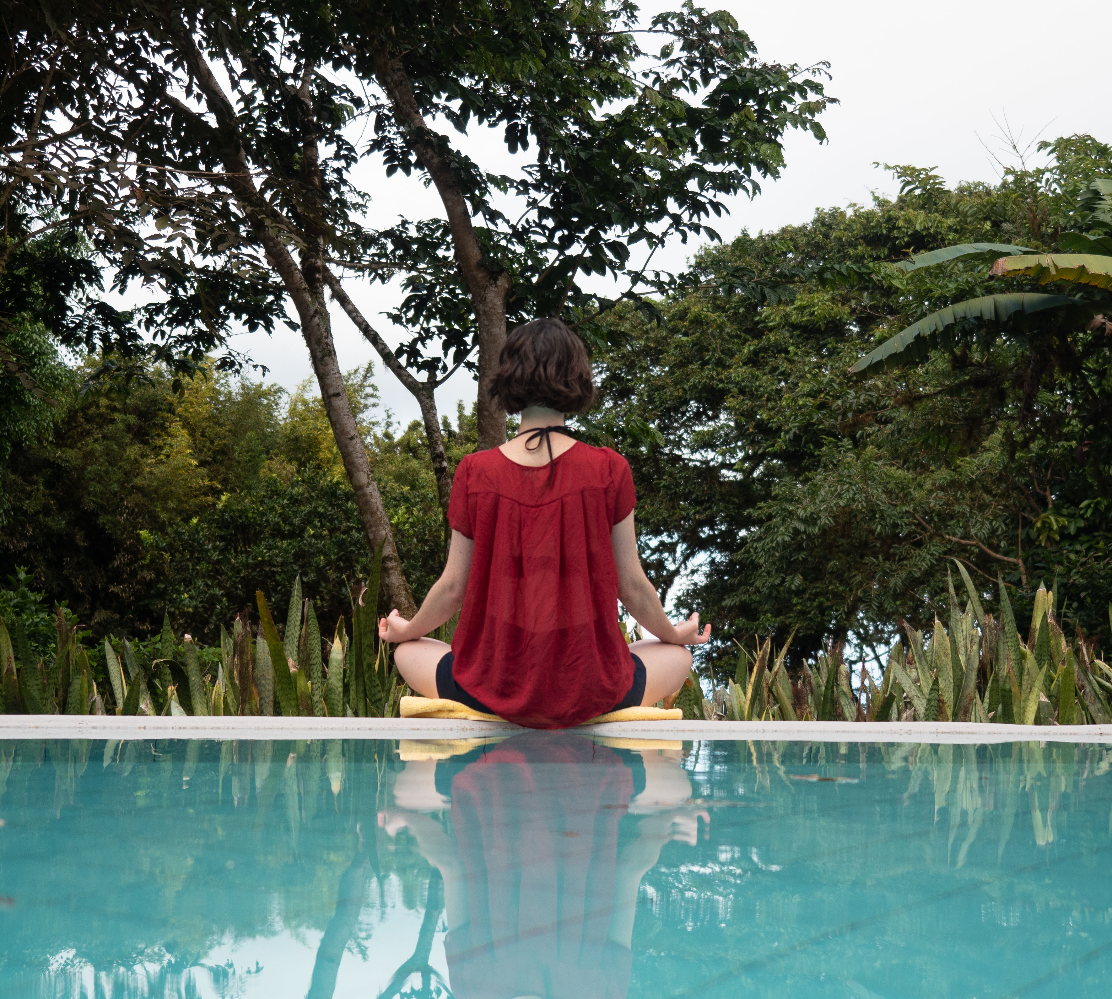 A woman doing yoga by the resort pool