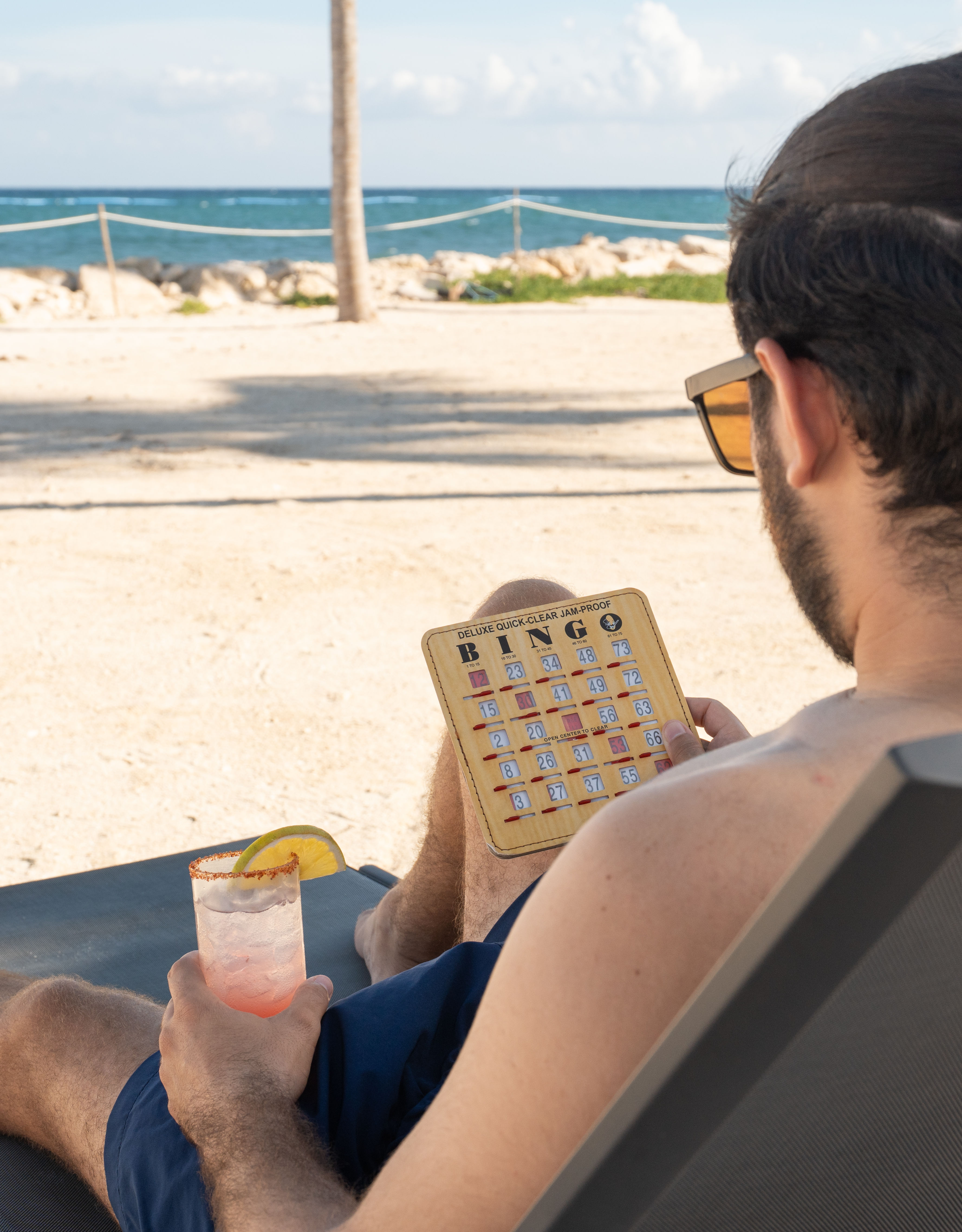 Man Lying on a Lawn Chair  at the Beach Playing Bingo