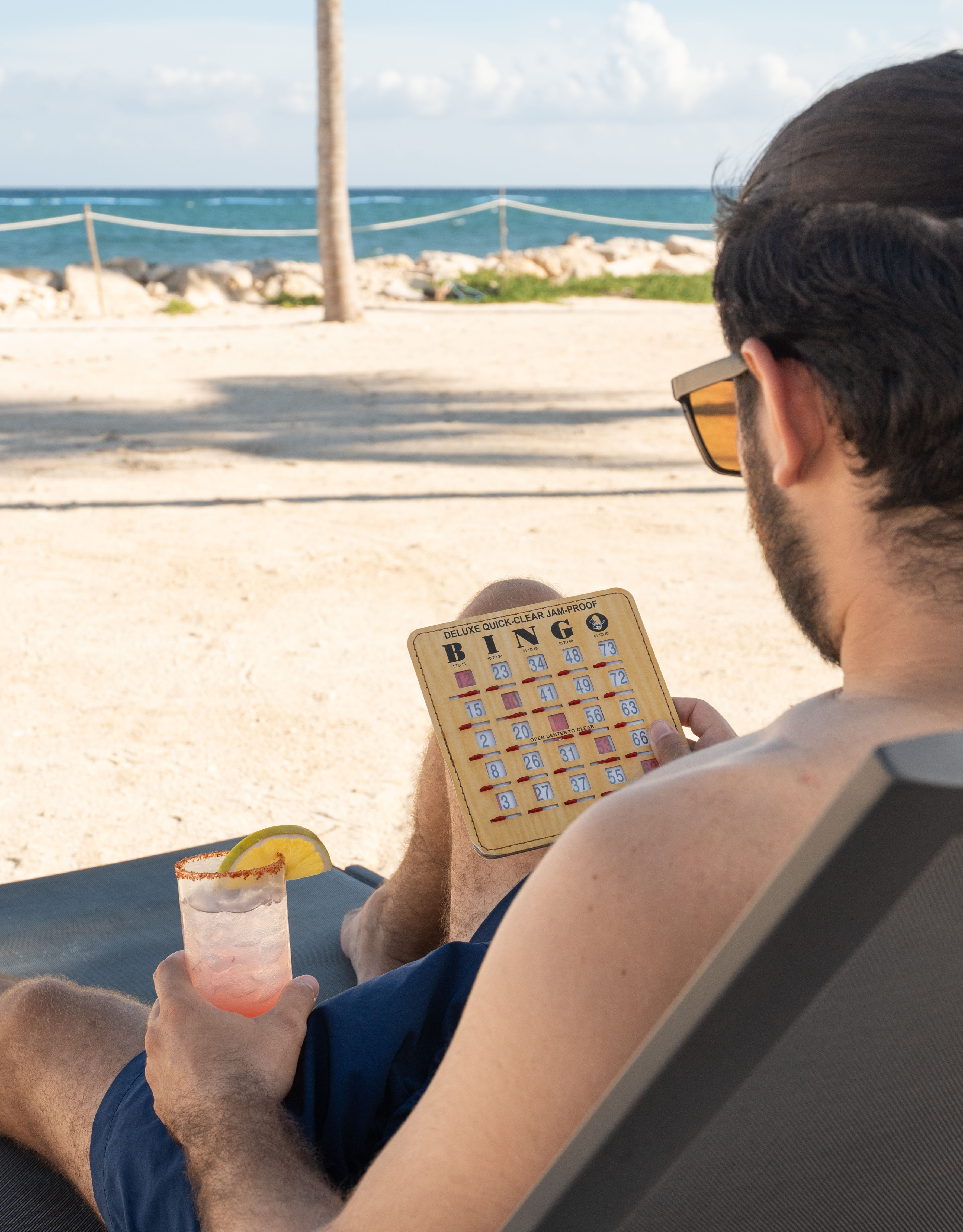 Man Lying on a Lawn Chair  at the Beach Playing Bingo