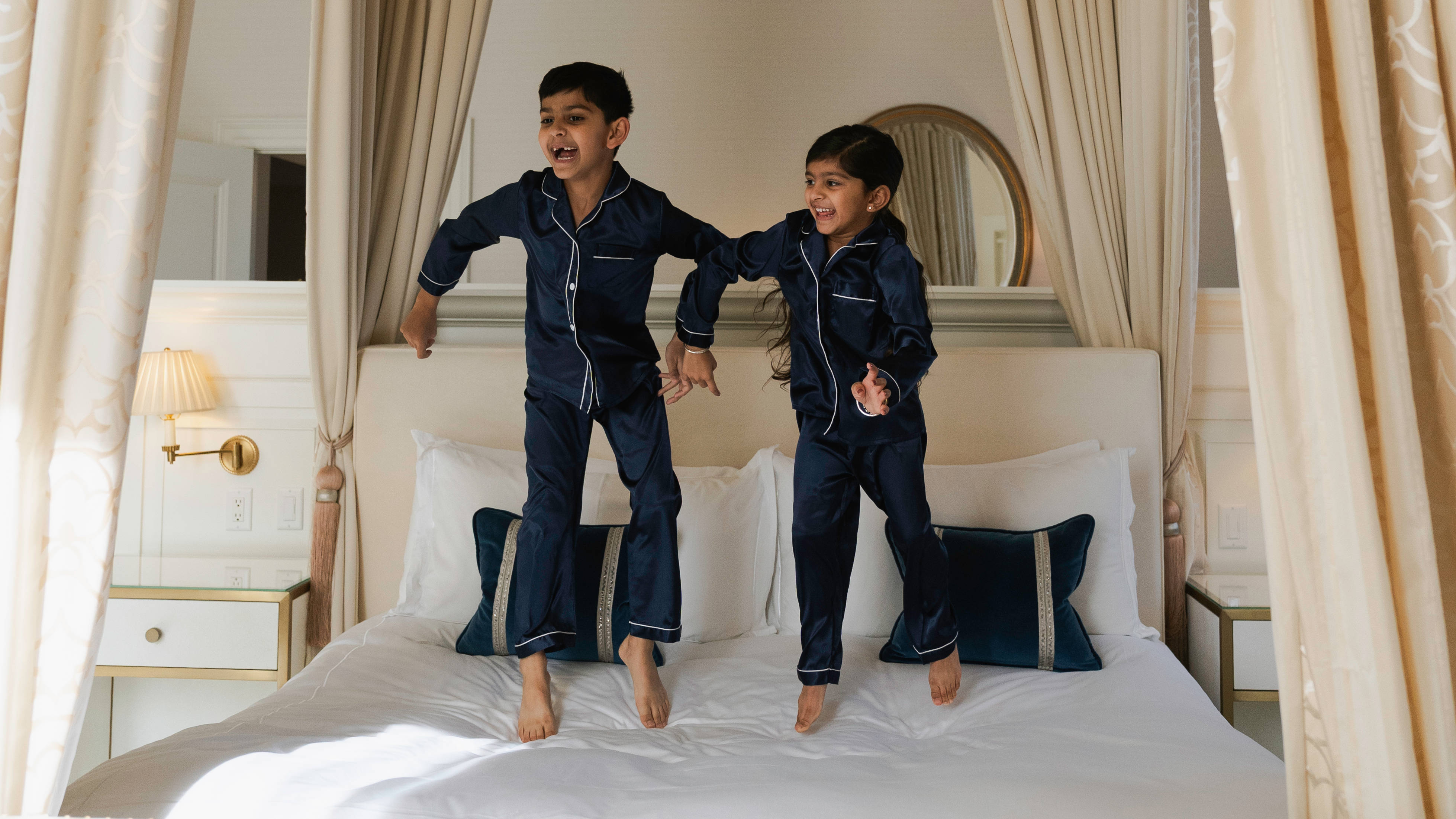 Băieți jucându-se pe un pat într-o cameră de oaspeți