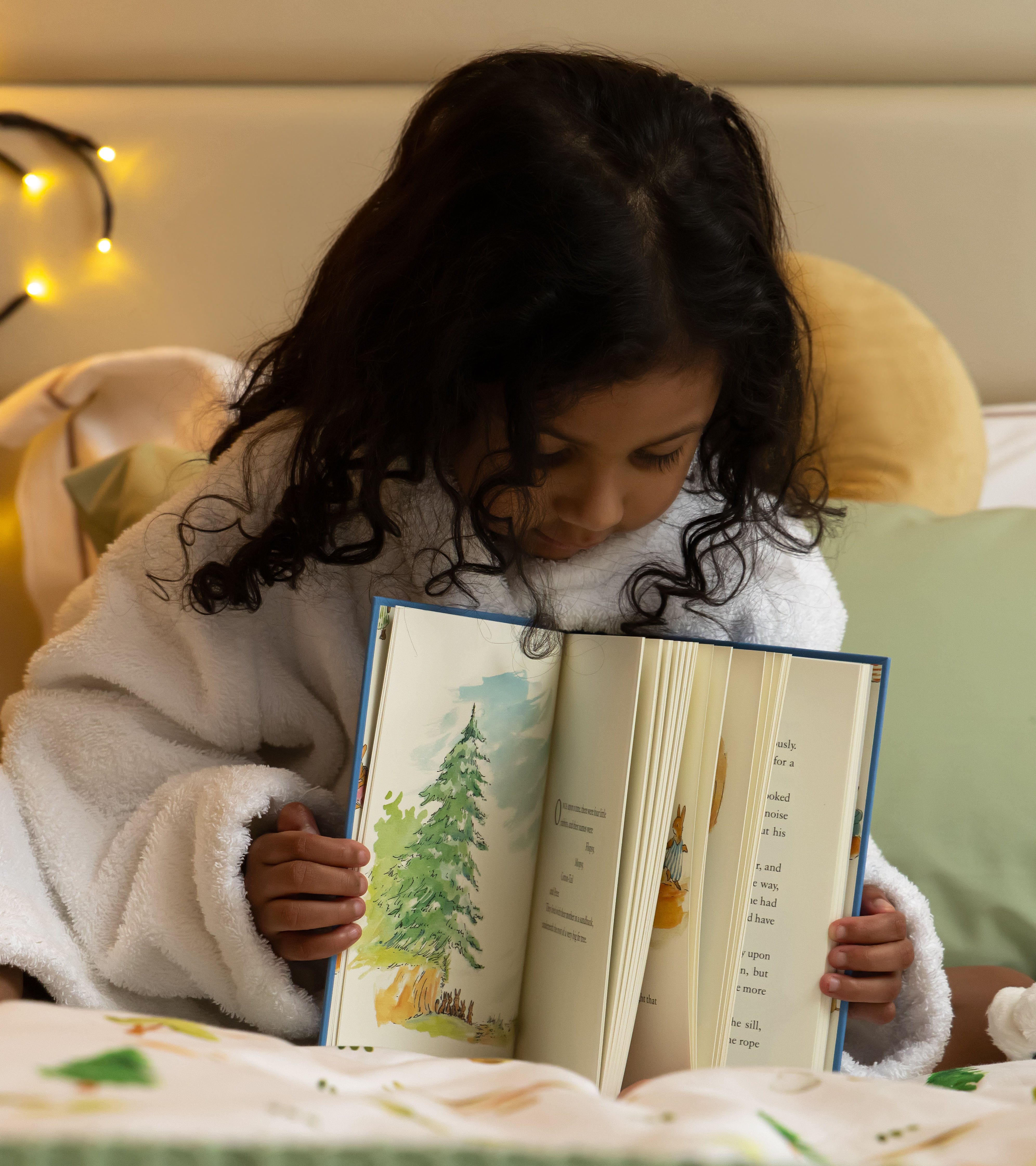 Child reading book on bed