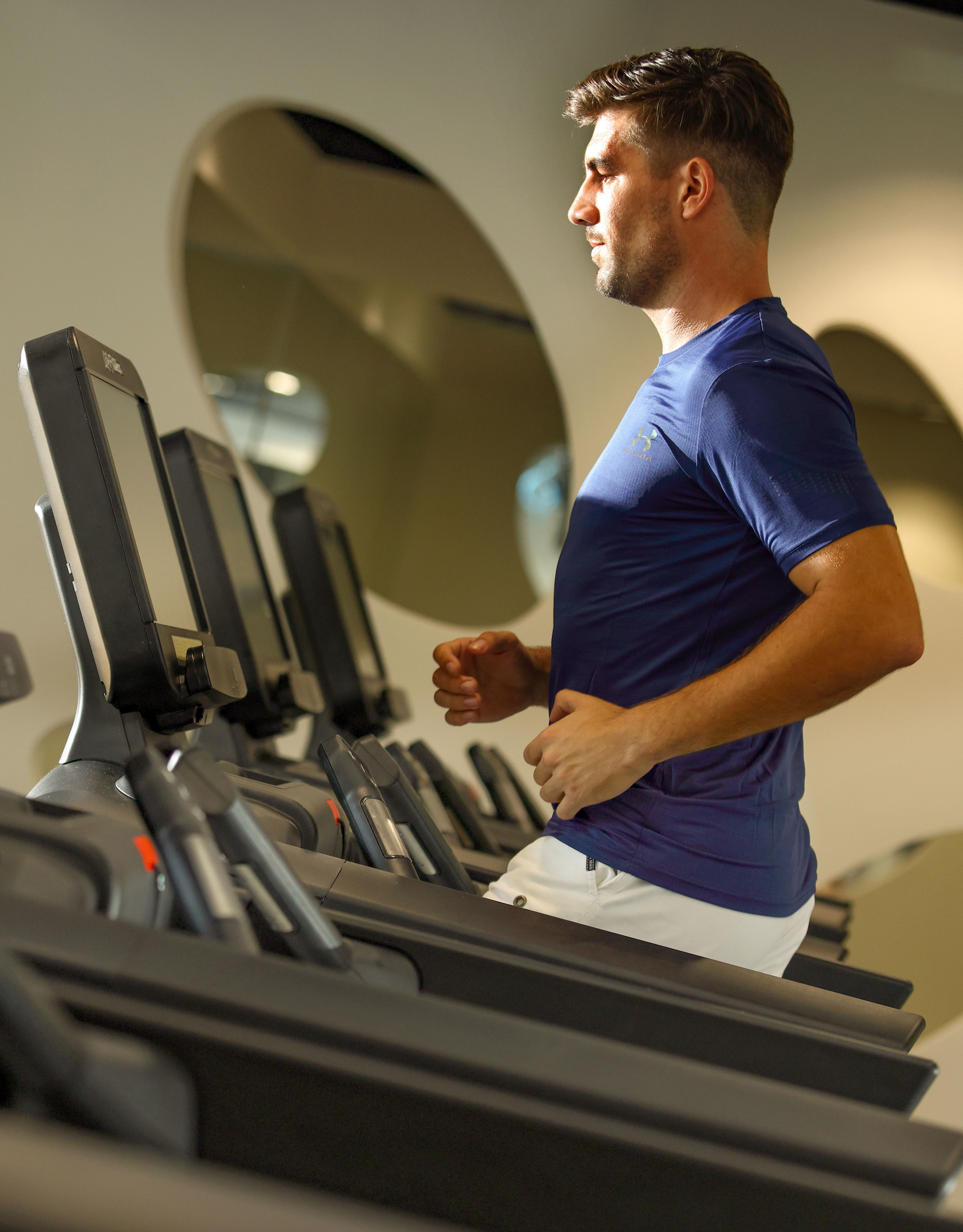 Mann auf Laufband inmitten einer Reihe anderer Laufbänder.