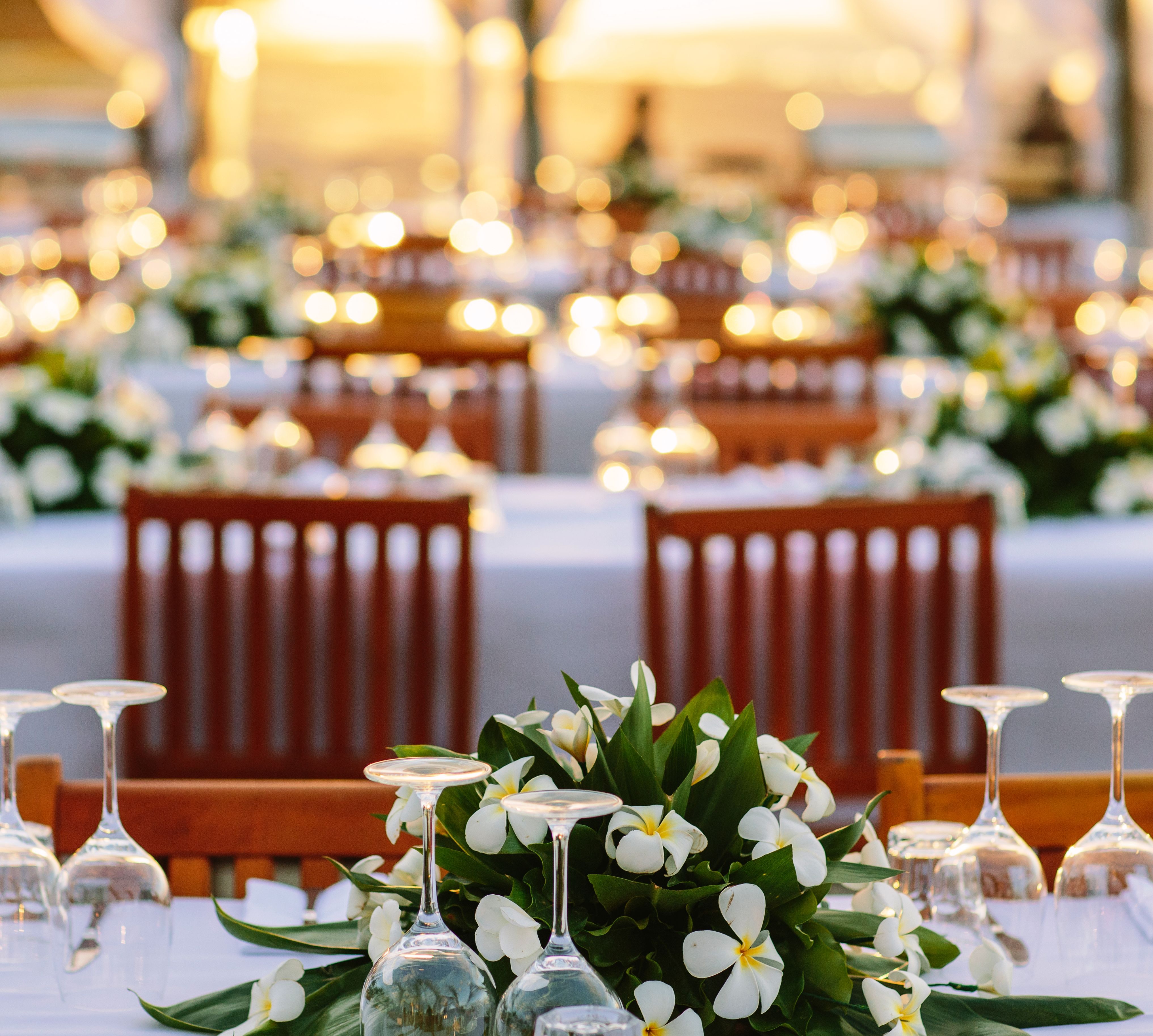Detailed View of Dining Table With Flowers and Wine Glasses Set Up for Event On the Beach