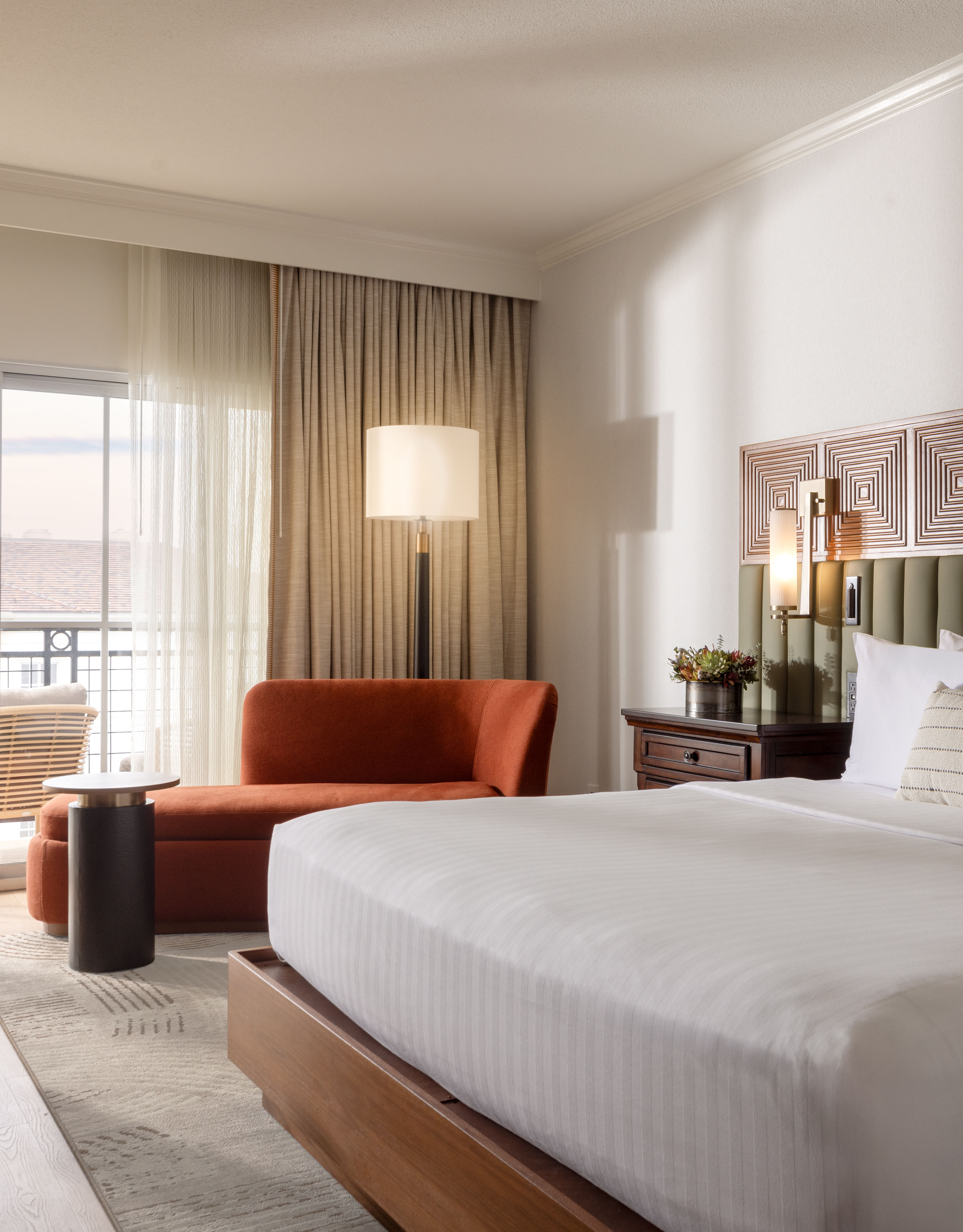 Guest room with king bed, chaise lounge, work desk and balcony