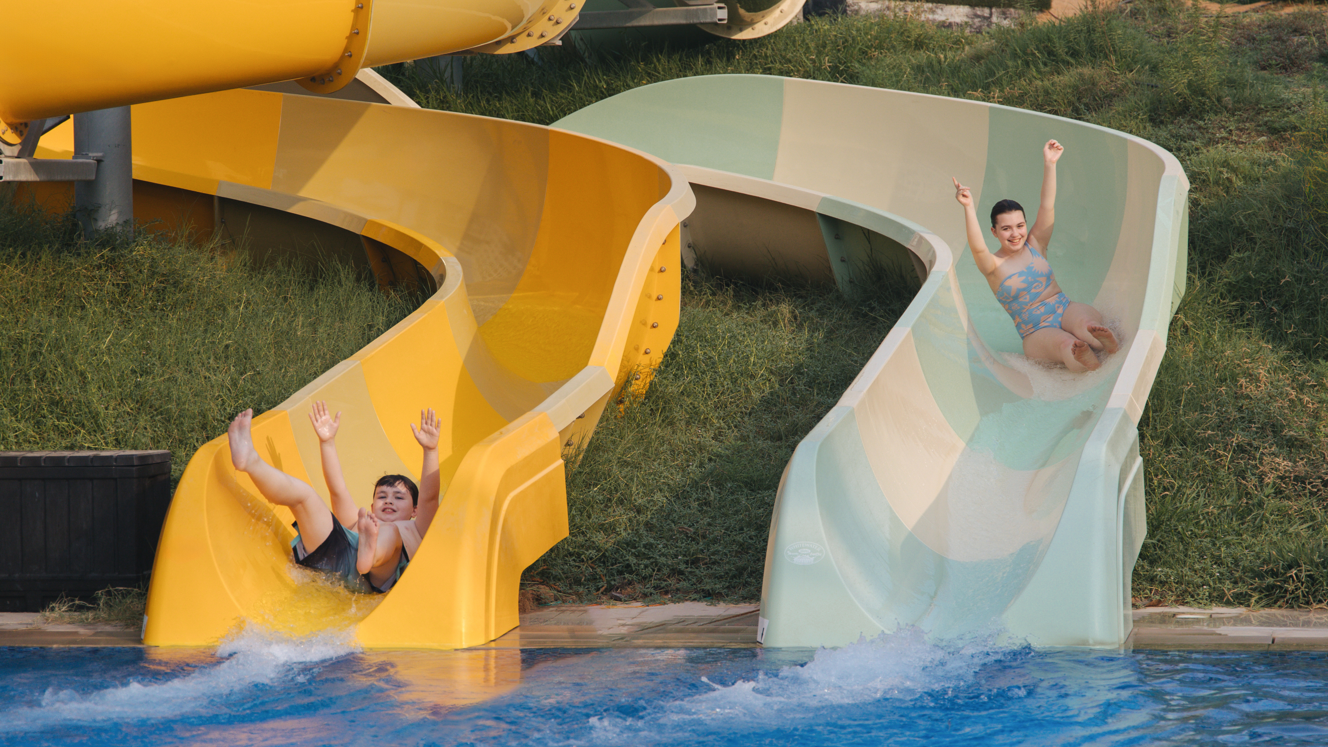 Two children sliding down two slides
