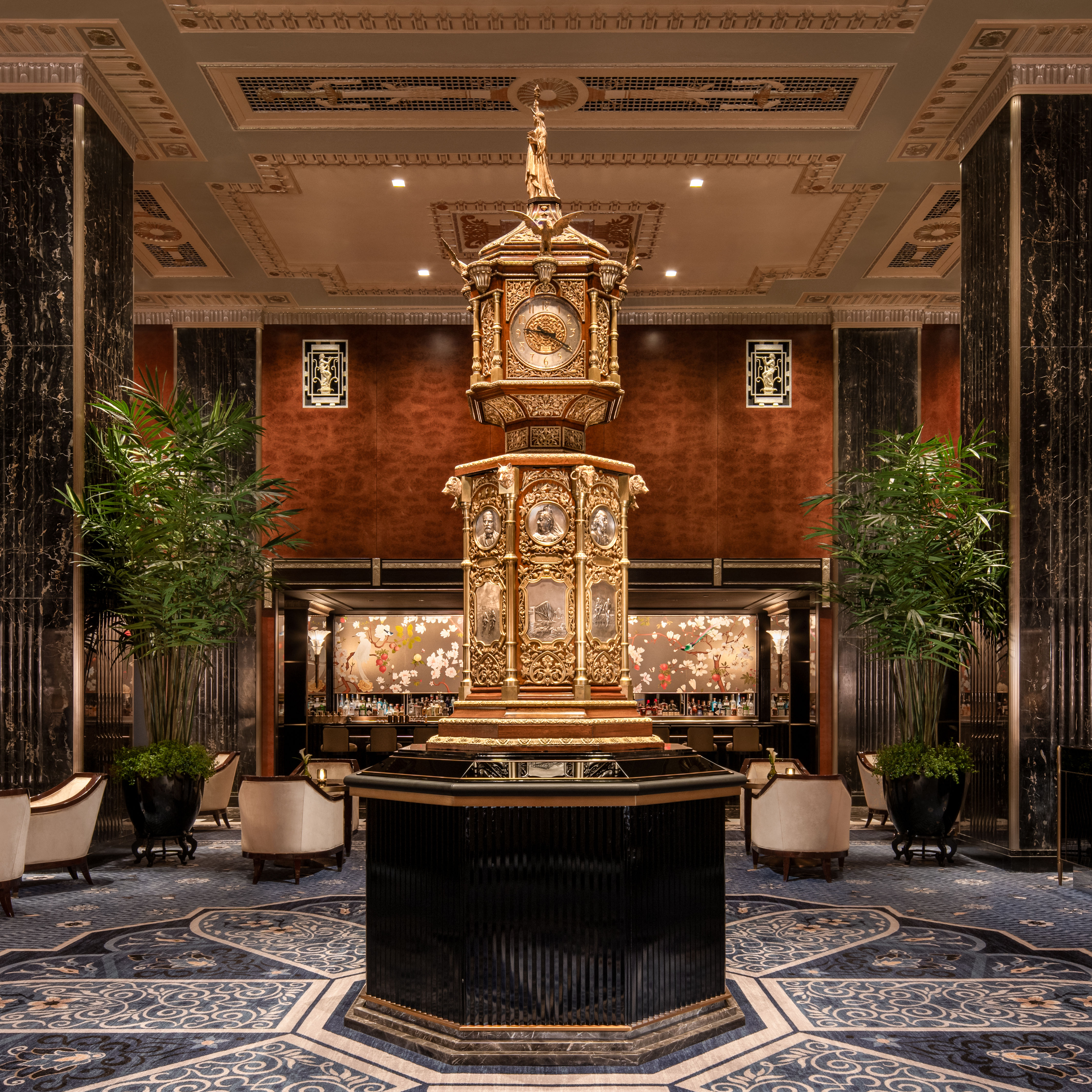 Luxurious lobby area with ornate clock, seating area, plants and pillars