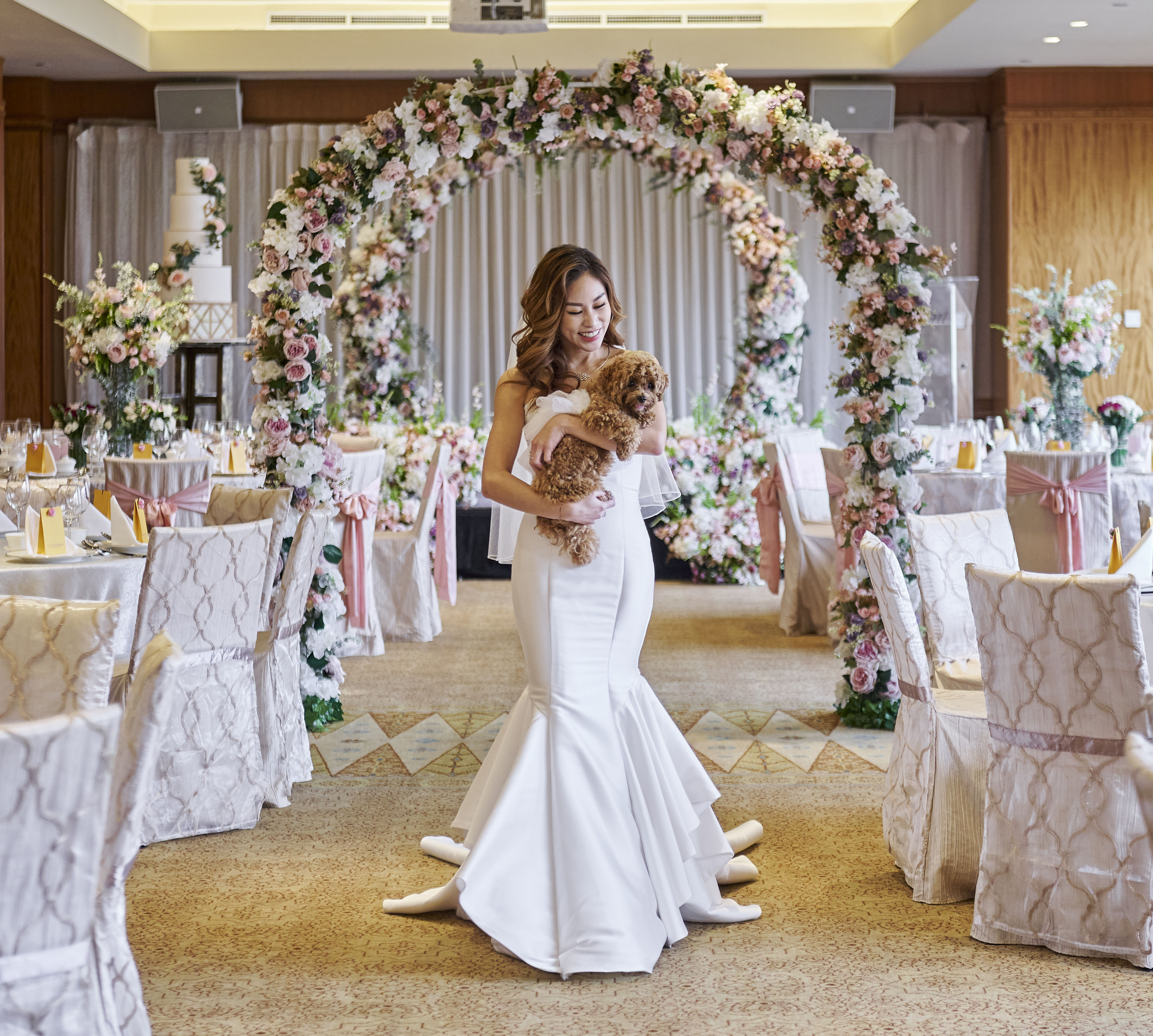 Asian bride in a white wedding dress craddling a small dog in the Tanglin meeting room