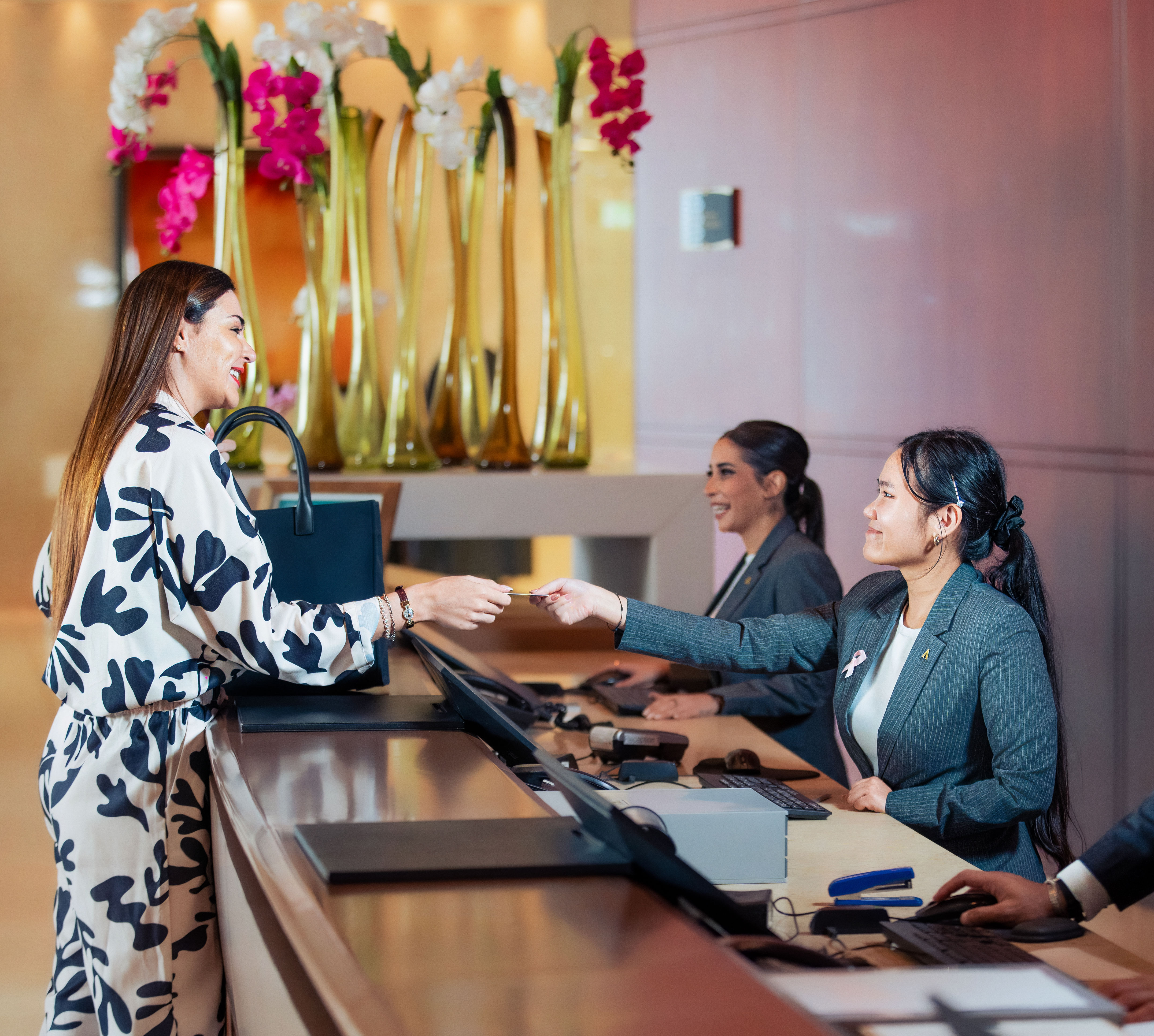 Guest at the front desk with three team members behind the desk