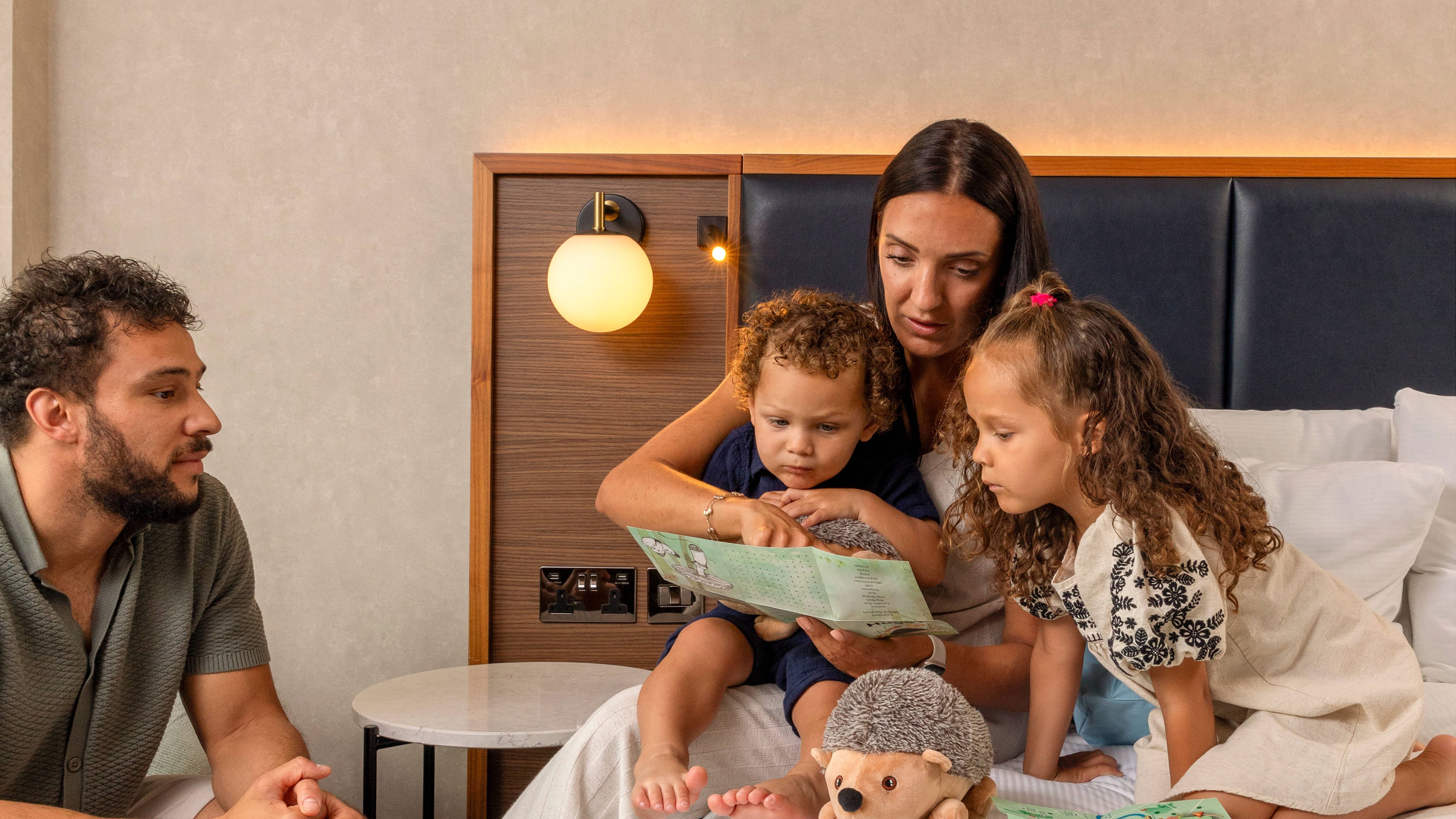 Family Reading to Their Children in a Guest Room 
