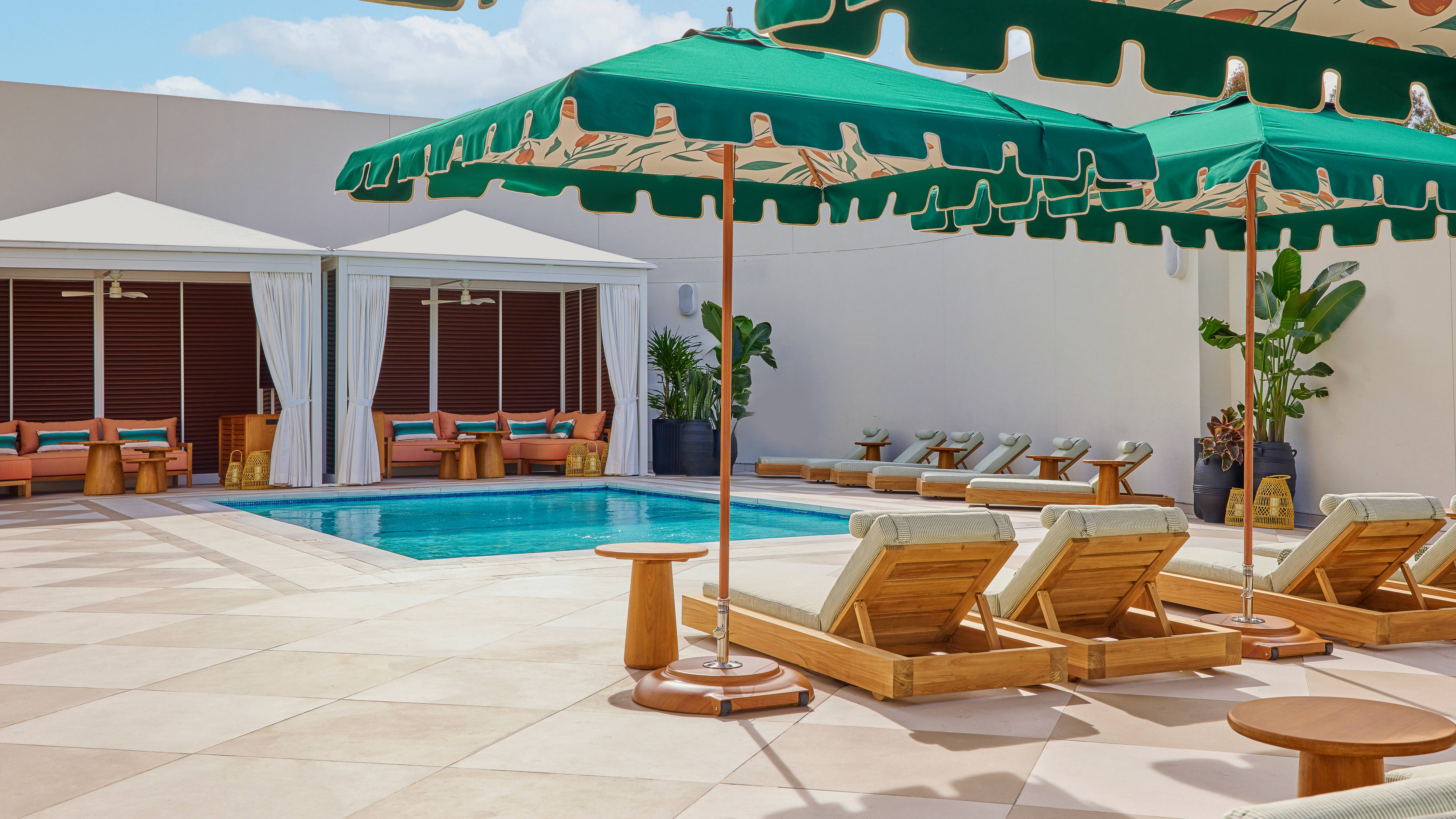 Outdoor Pool Area with Cabanas and Lounge Chairs under Umbrellas