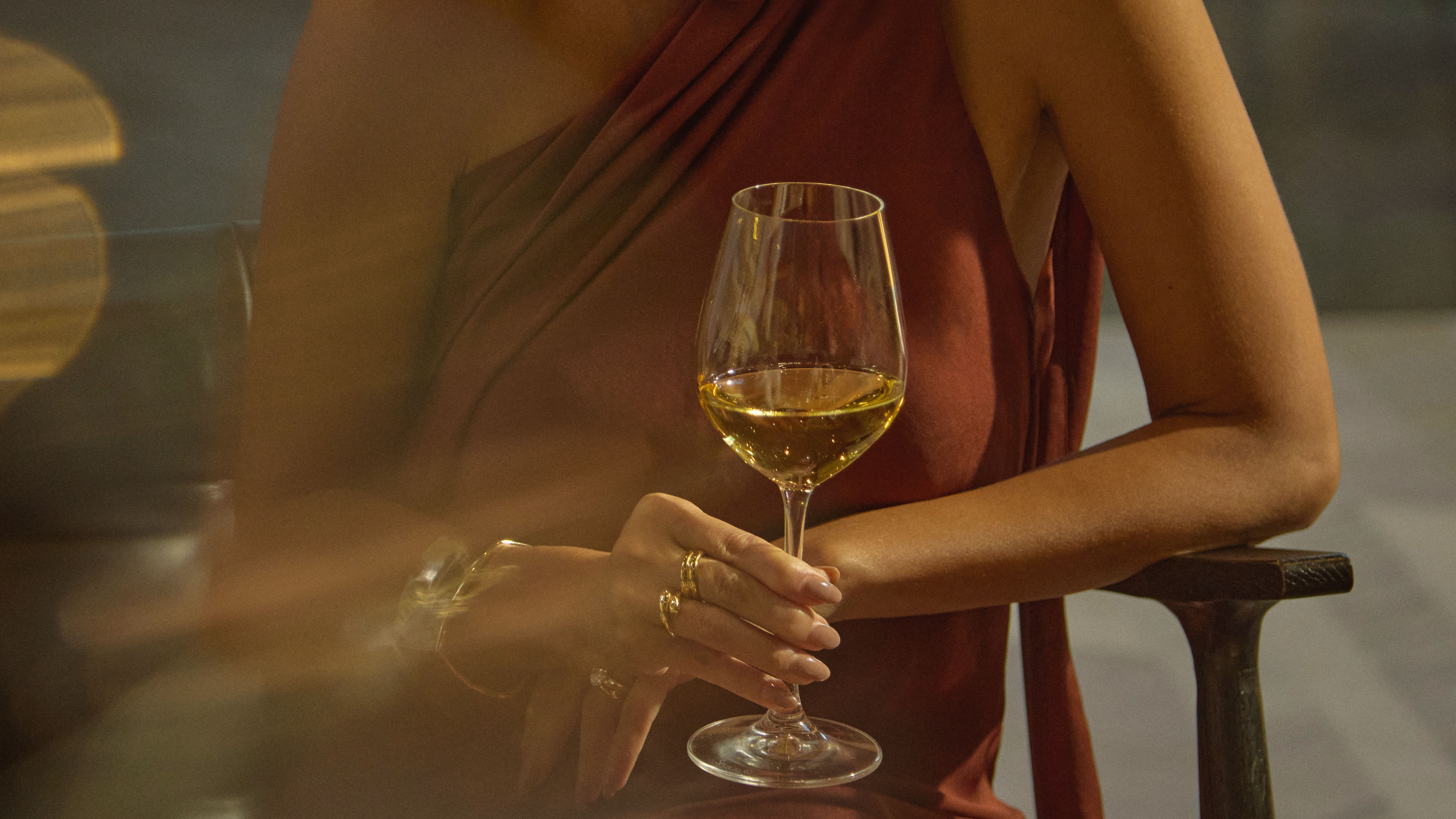 Prim-plan portret al unei femei într-o rochie elegantă de seară bucurându-se de un pahar de vin alb în Ceiba Club