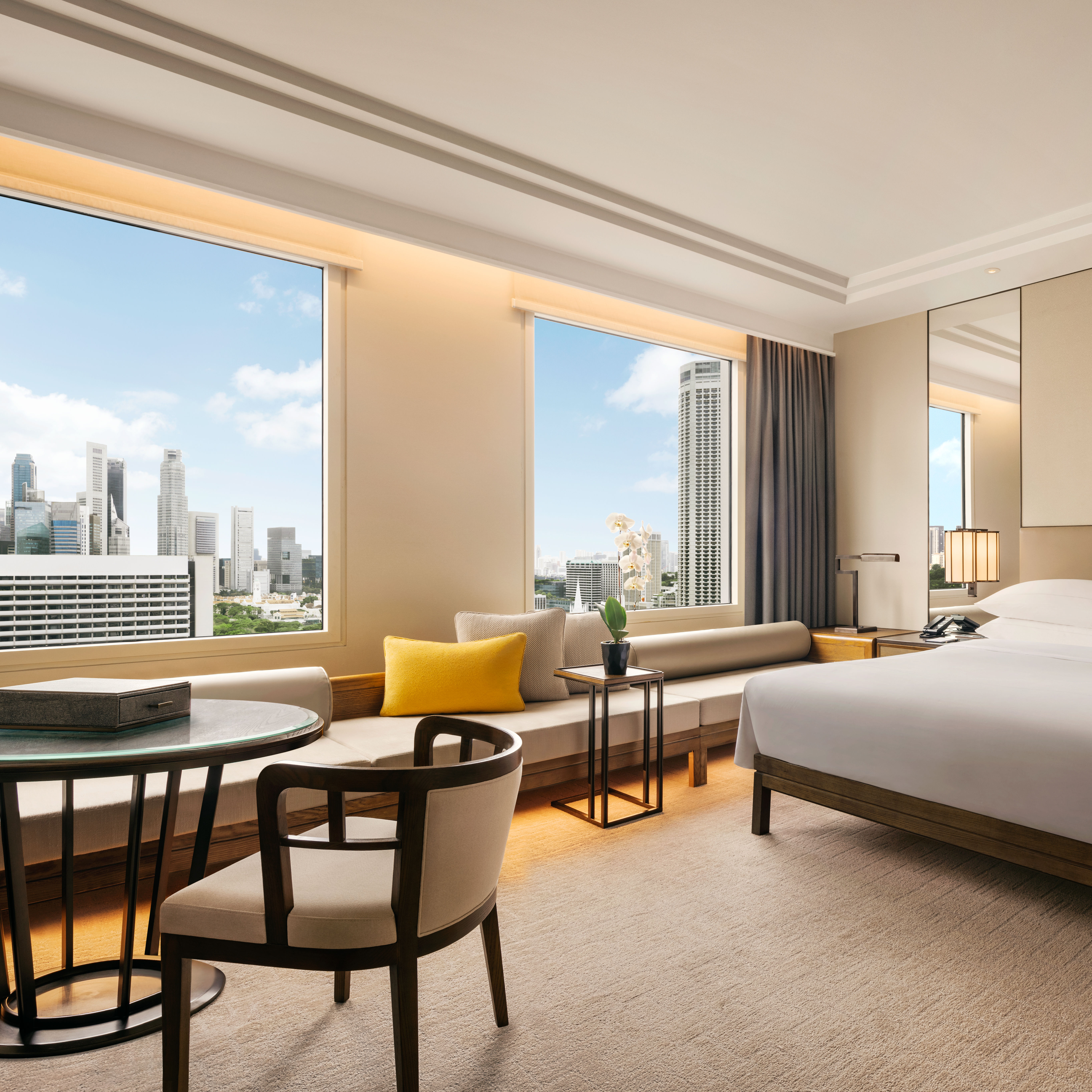 Grand lit et espace salon dans une chambre avec vue sur la ville