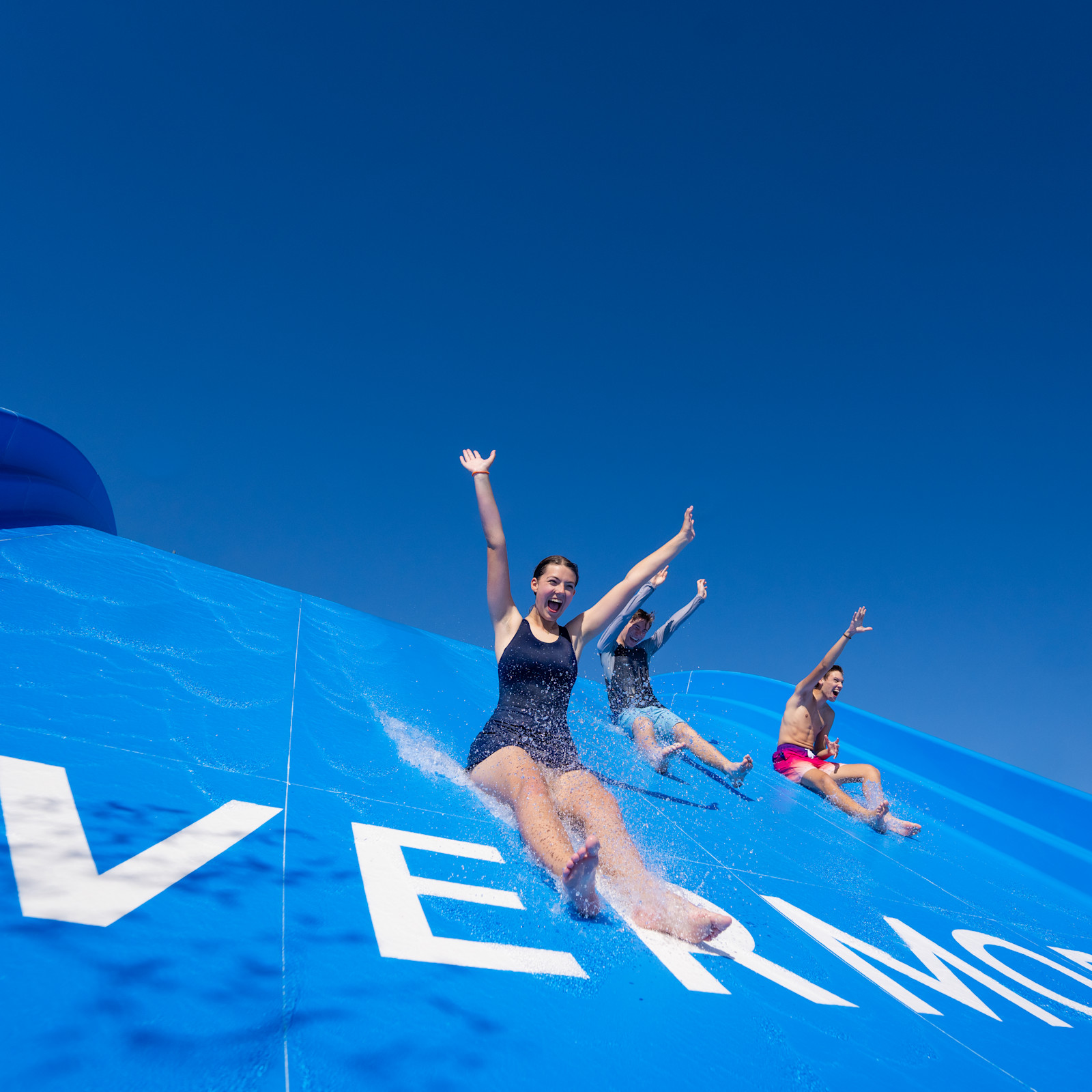 Üç kişi su kayağından inerken kollarını gergin tutarak gülüyor