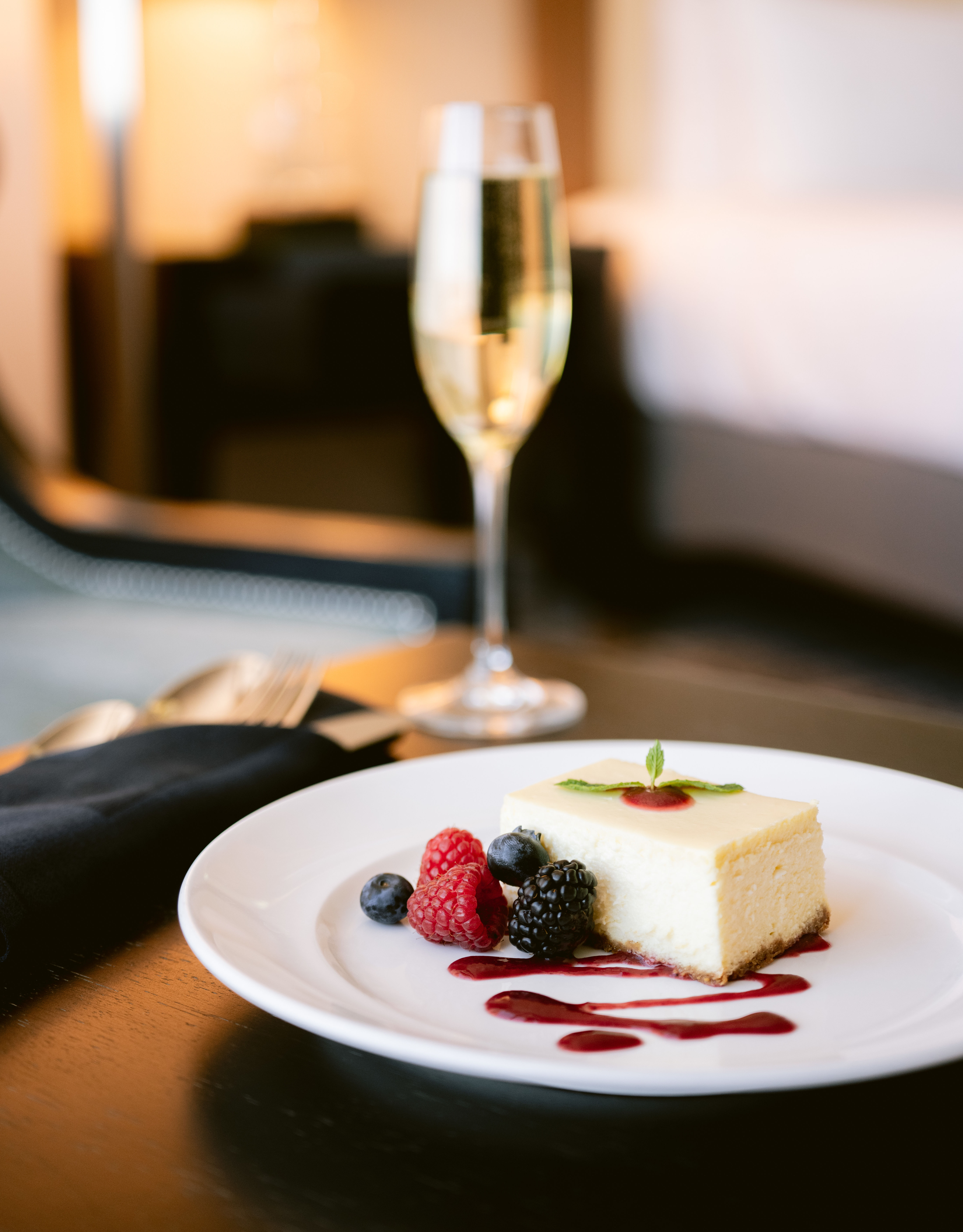 In-Room Dining, cake and berries on a plate, and a glass of white wine on a table in a guest room