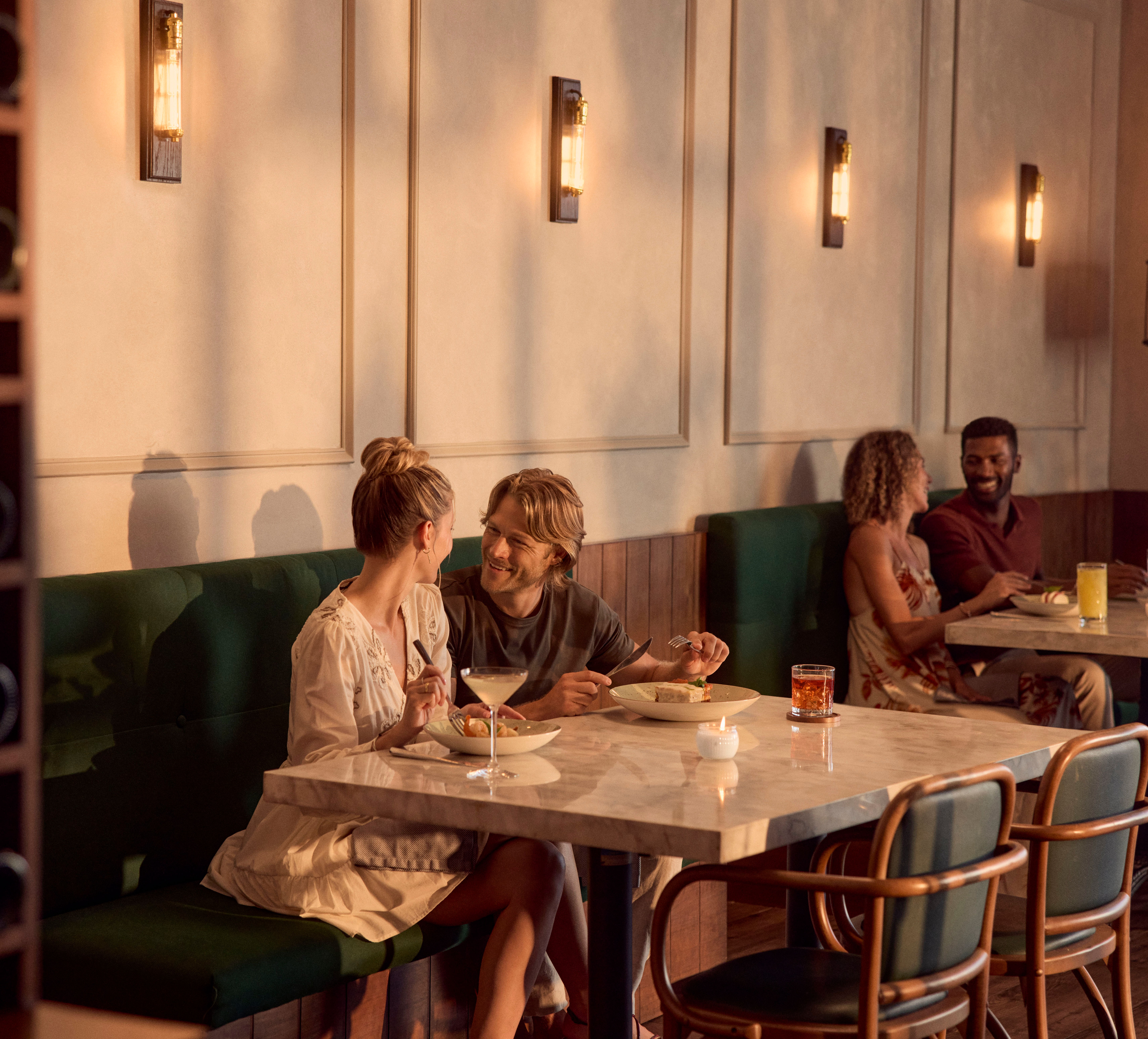 Un homme et une femme savourant un dîner et des boissons au restaurant de l'hôtel