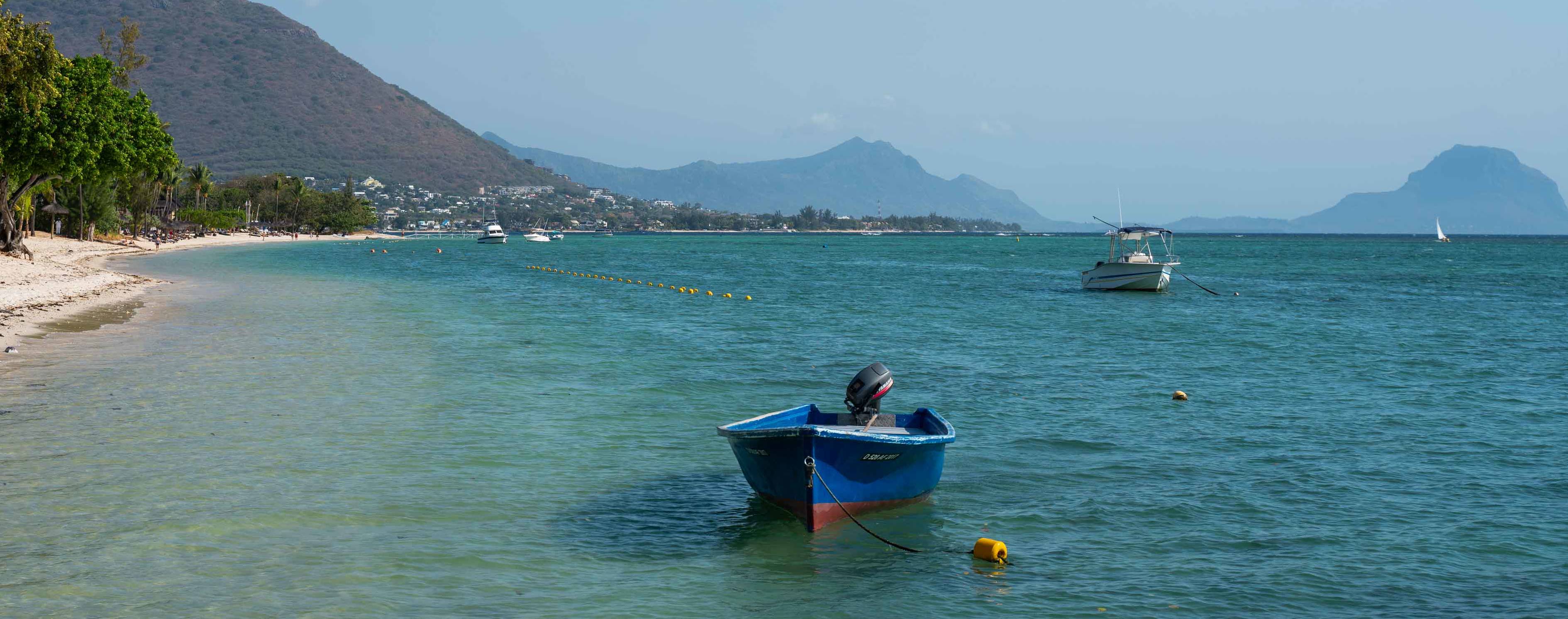 Plage avec des bateaux sur l'eau et vue sur les montagnes en arrière-plan 