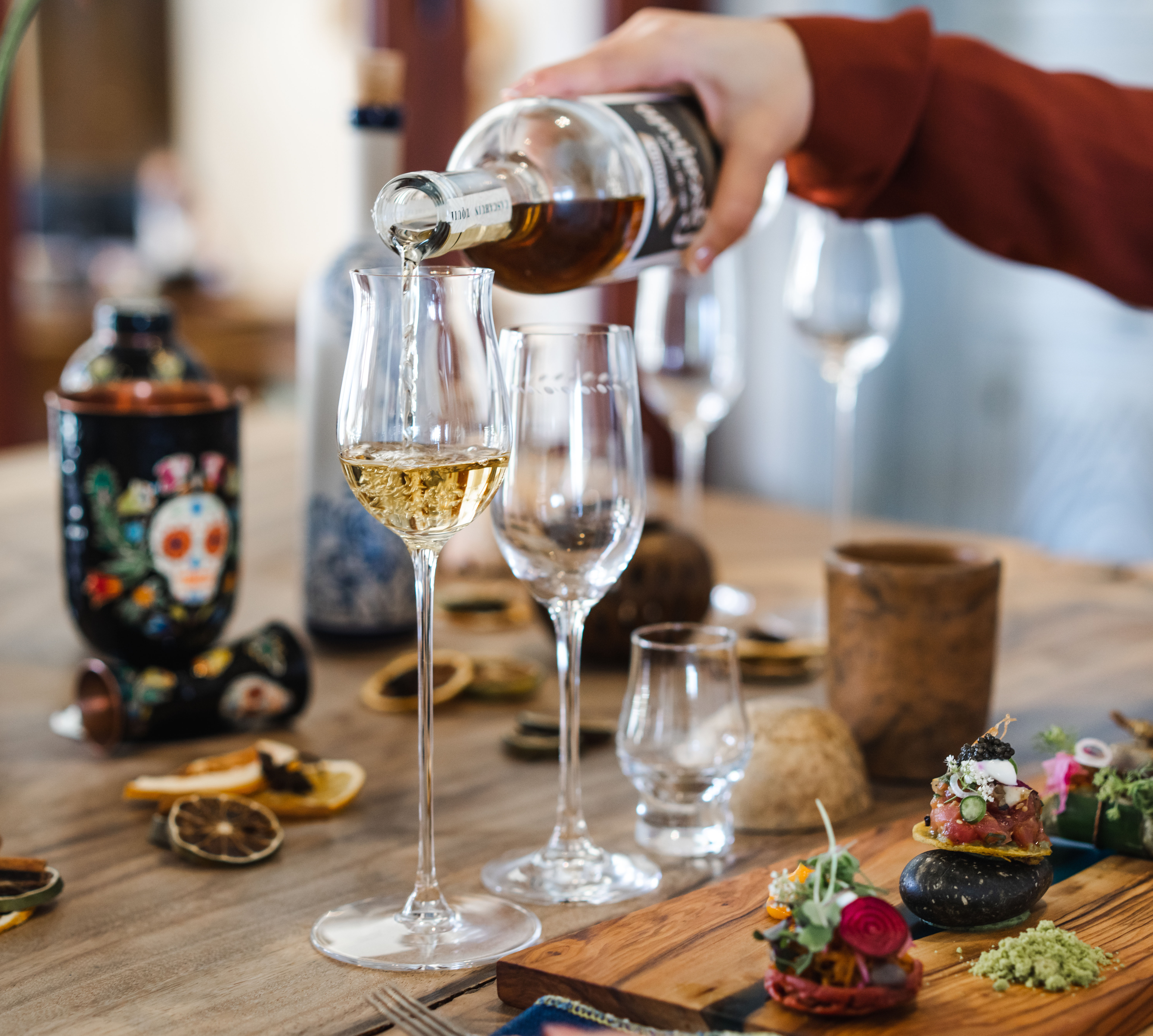 Gießen eines Getränks in ein Glas am Tisch mit Vorspeisen