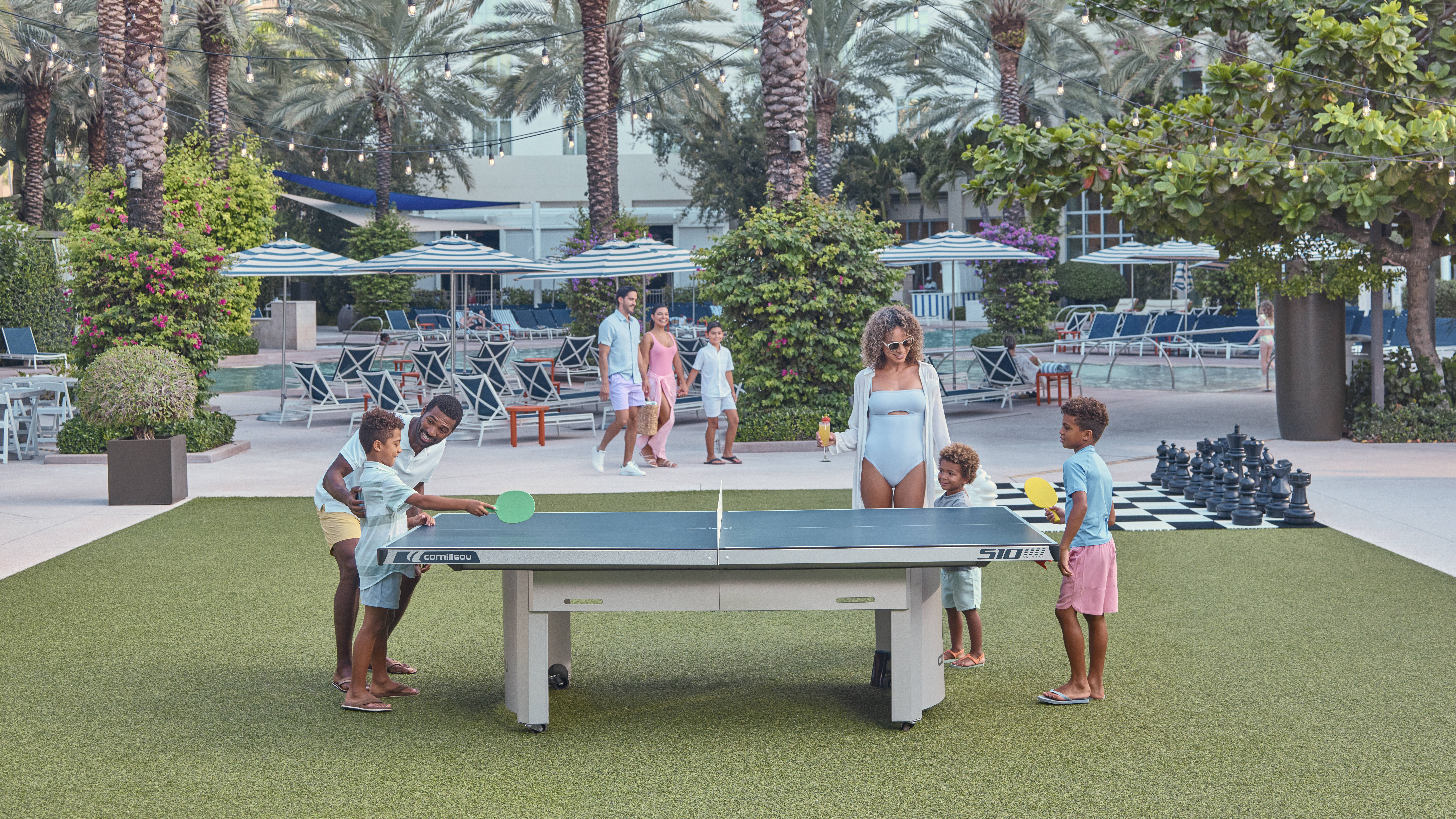 Family Playing Ping Pong on Outdoor Area with Palm Trees
