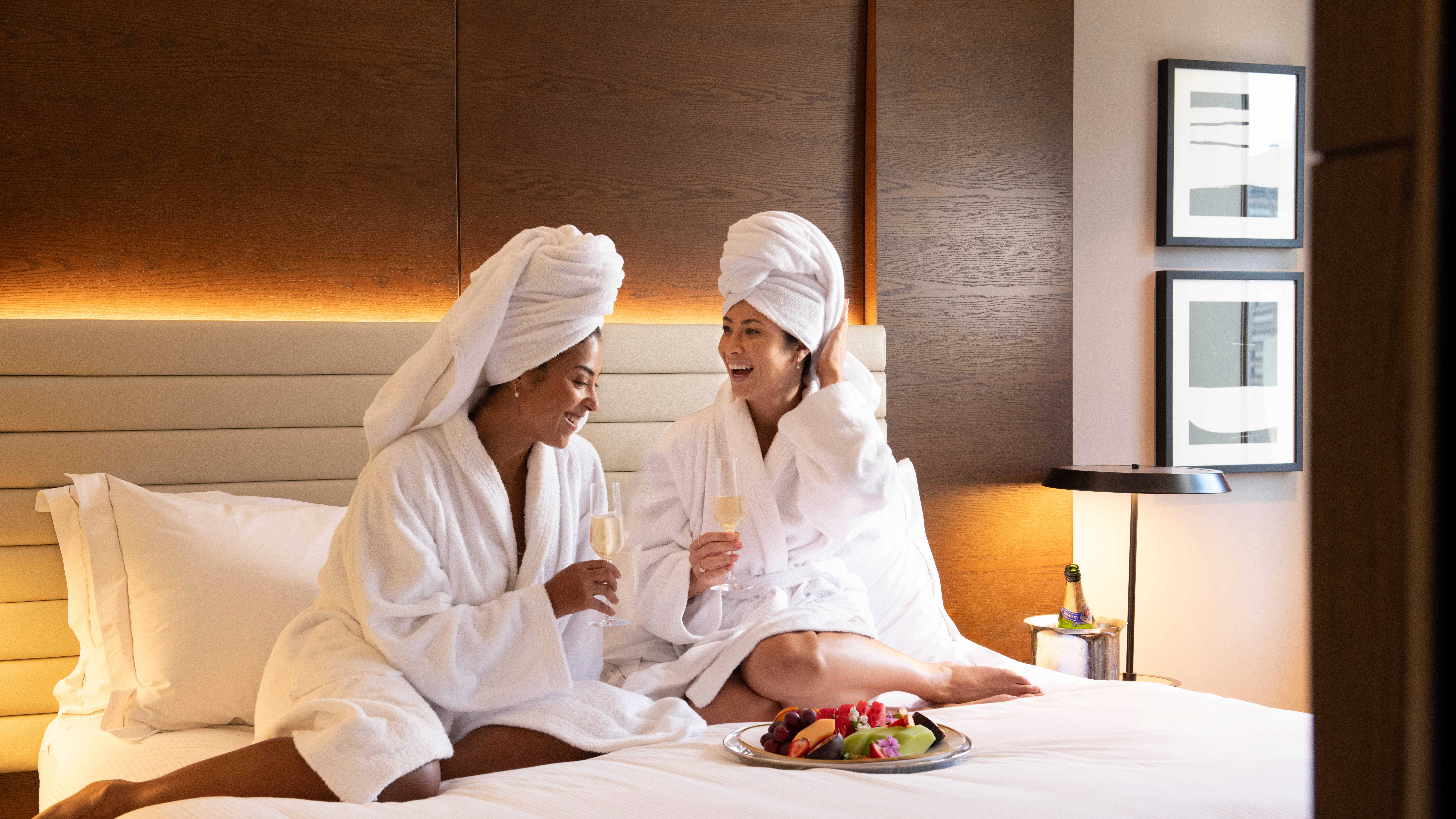 Două femei luând masa în pat într-un apartament