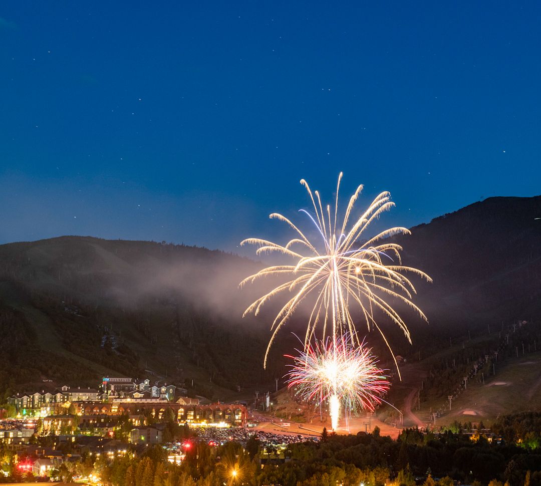 Aerial View of a City with Fireworks at Night, and View of Mountains in Background