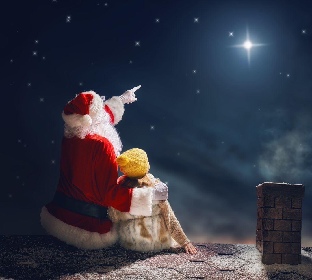 Santa sitzt mit einem kleinen Mädchen und zeigt auf einen Stern