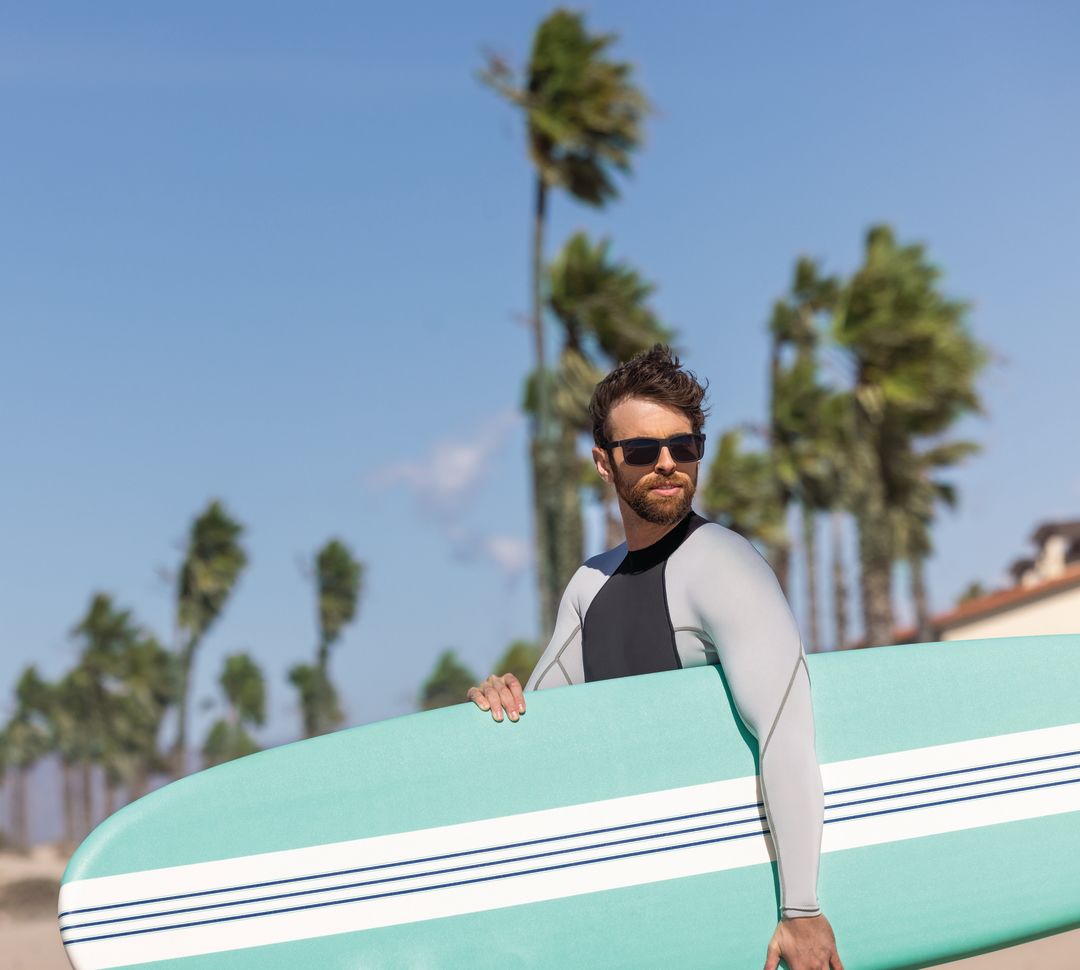 Man Holding a Surfboard at the Beach