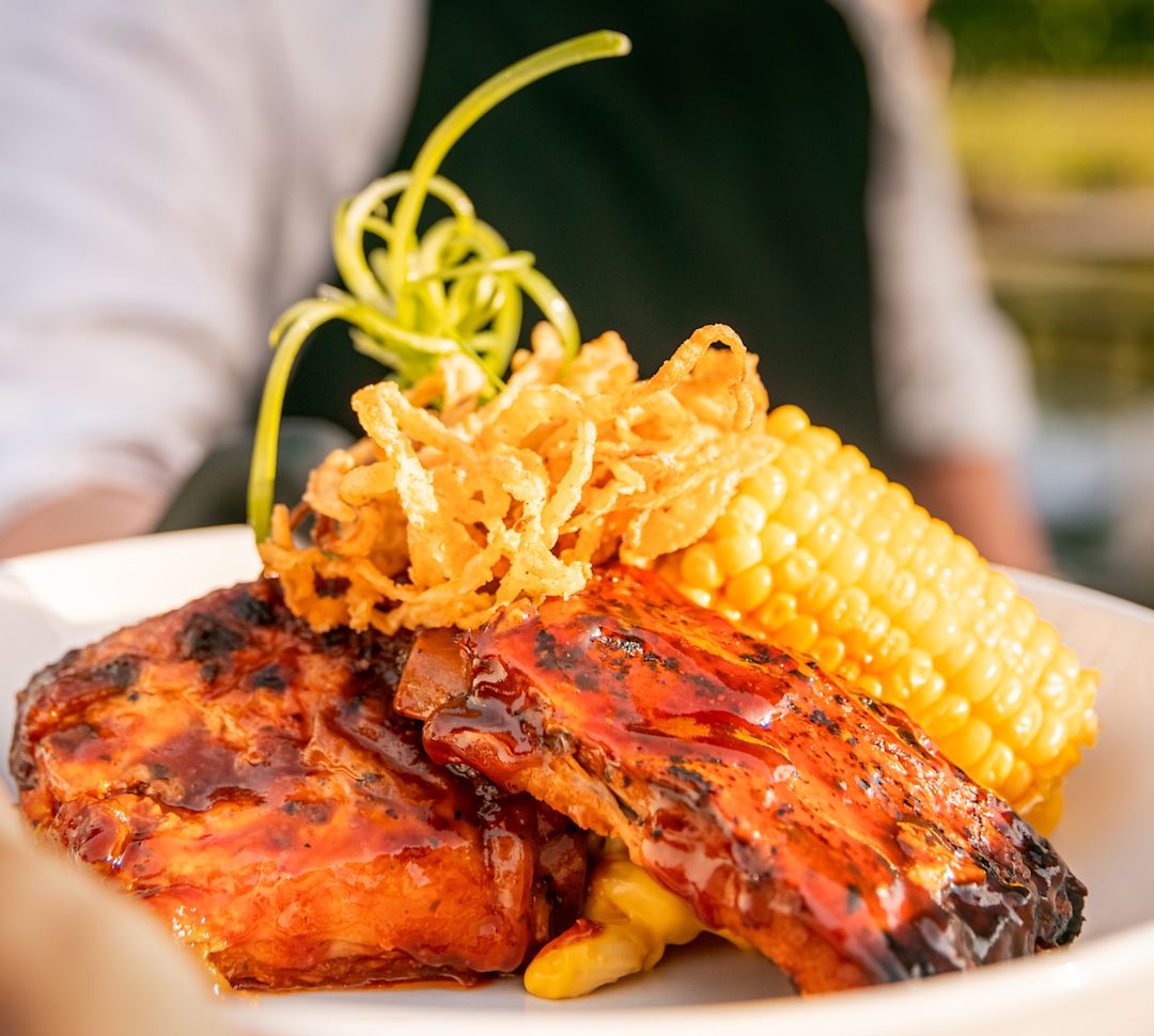 Person Holding a Plate with BBQ and Corn at Laguna Restaurant