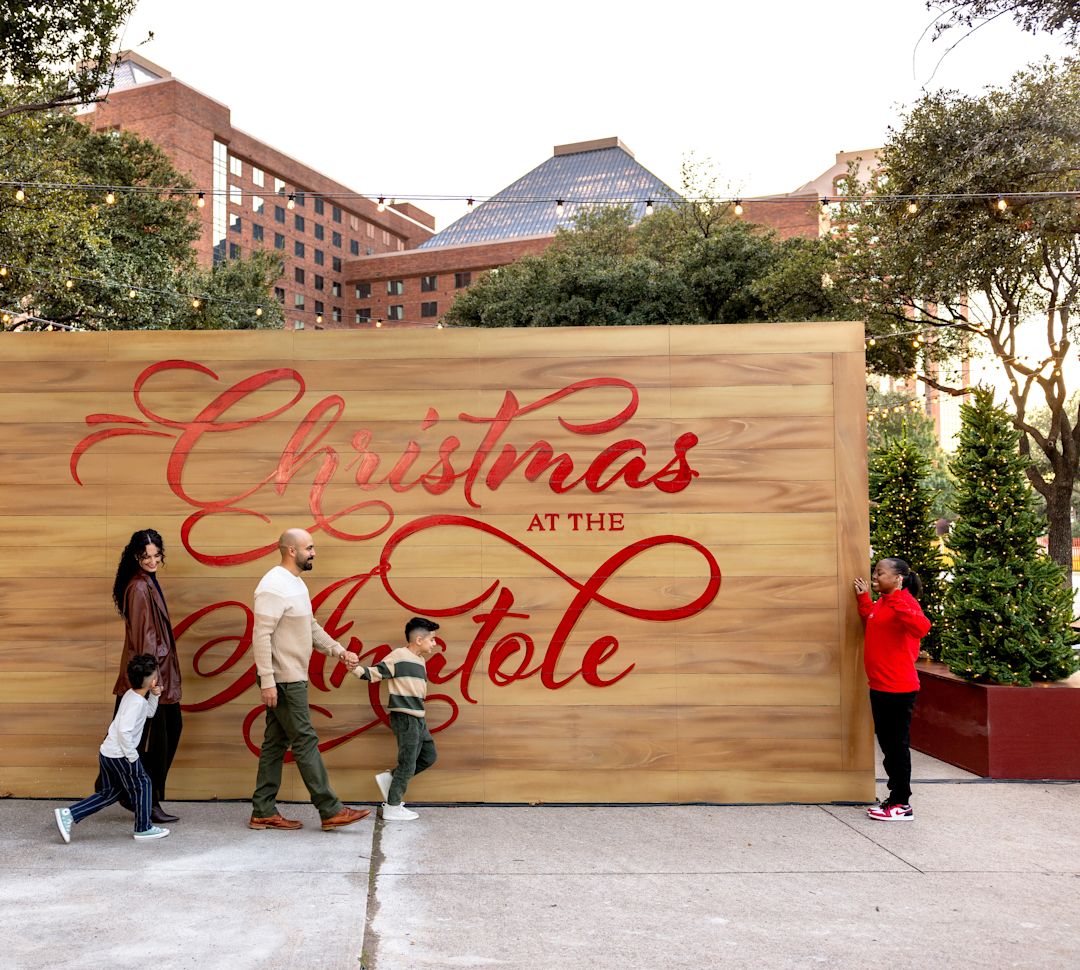 People Standing next to a Christmas at the Anatole Sign