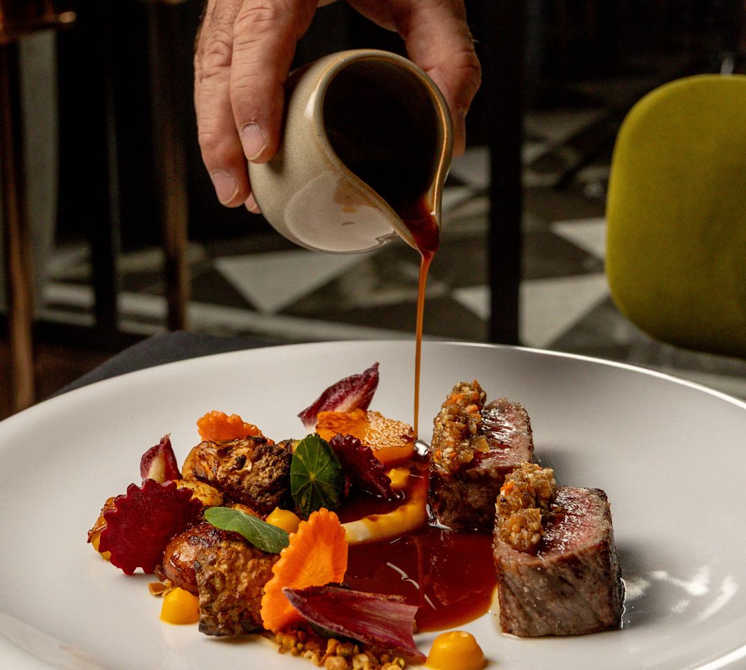 Verser la sauce à la main sur un plat sur une assiette au restaurant Stubborn Seed