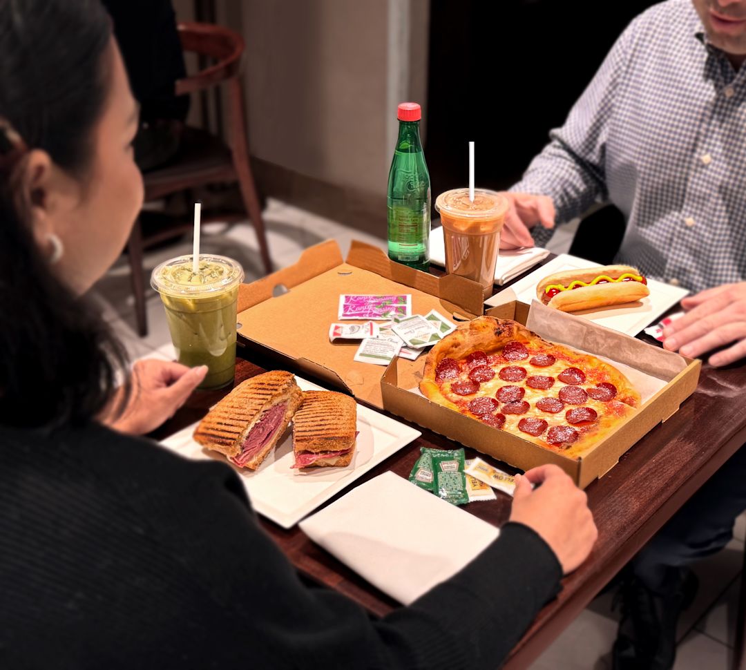 两个人坐在桌旁，享用Herb N' Kitchen的多种快餐。