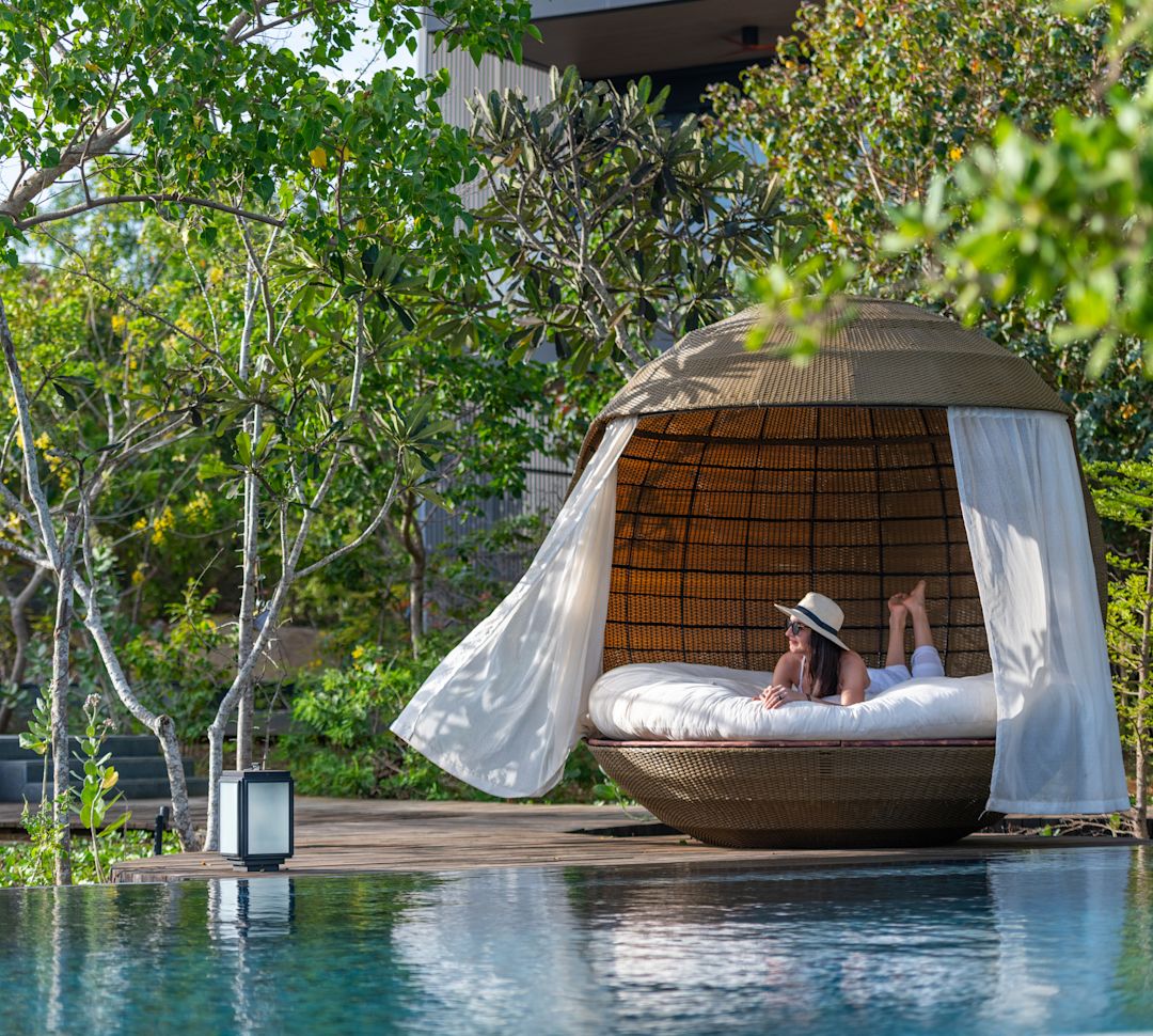 Person in pool lounge large wicker seating next to pool-transition