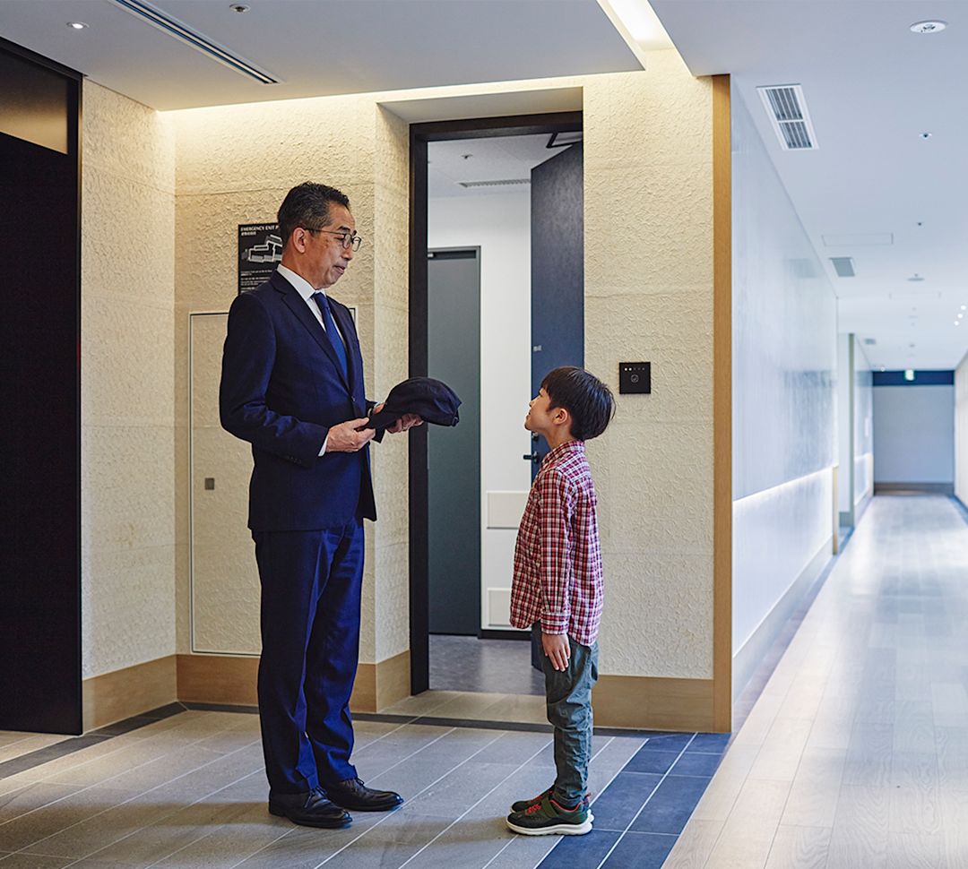 Mężczyzna w garniturze stojący przed młodym chłopcem, trzymający czapkę