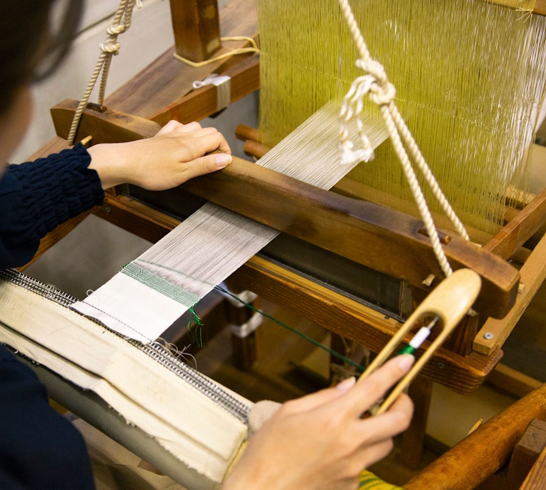 ผู้หญิงกําลังใช้เครื่องทอผ้า