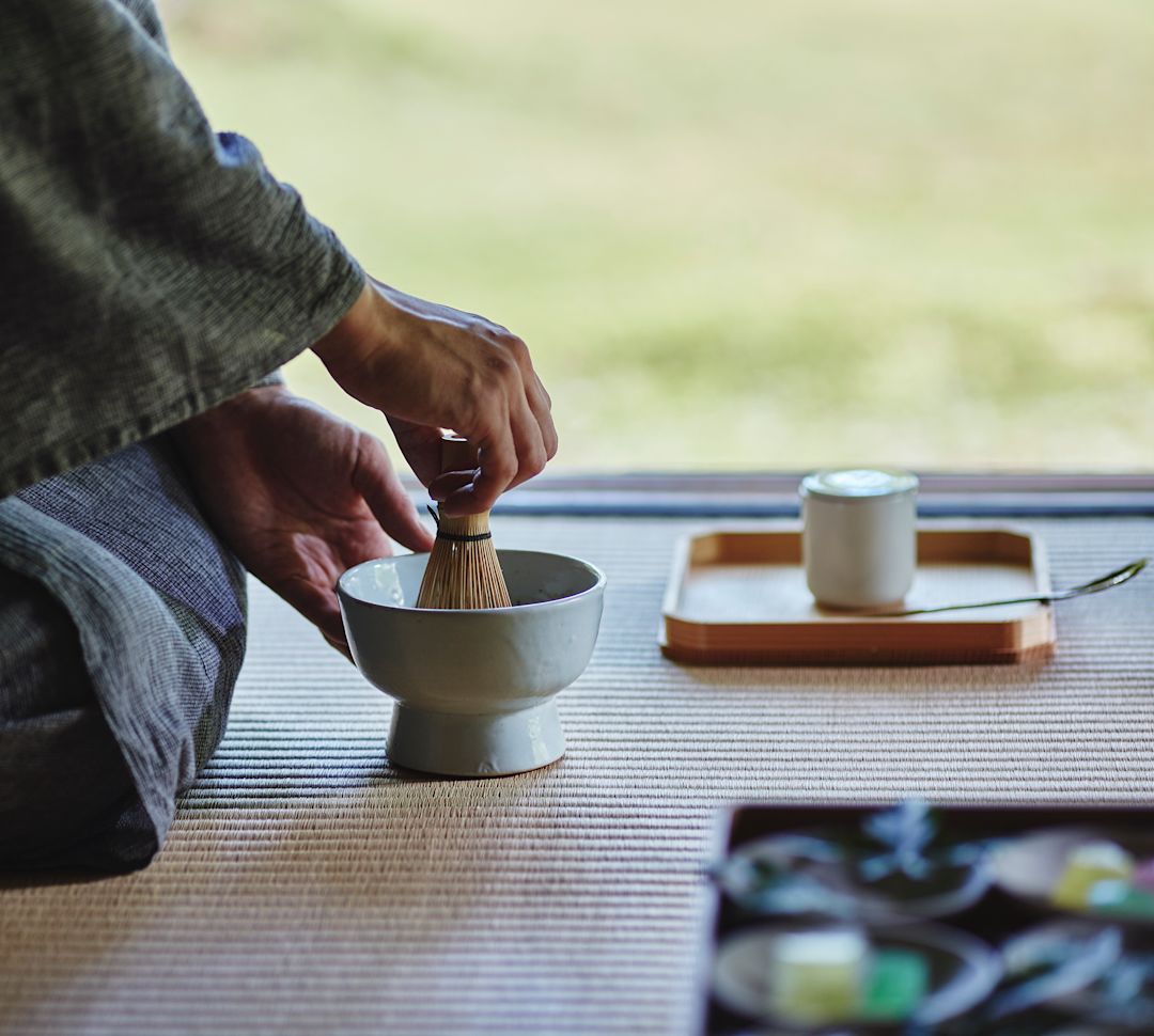 Osoba klękająca na podłodze przygotowująca herbatę