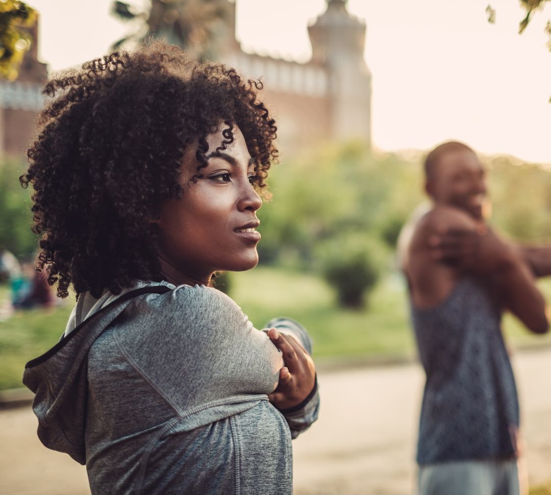 African American woman and man stretching before a run in a park