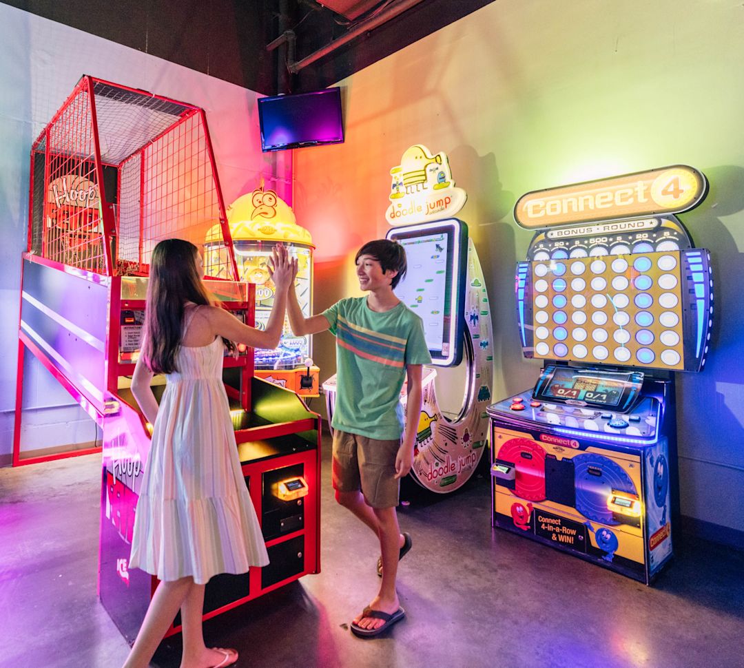 Dois jovens animados em um fliperama