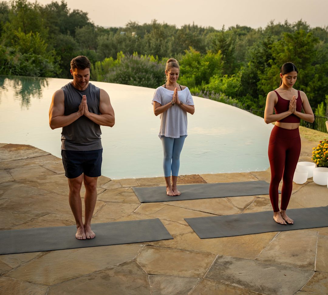 三个人在泳池旁边的户外做瑜伽