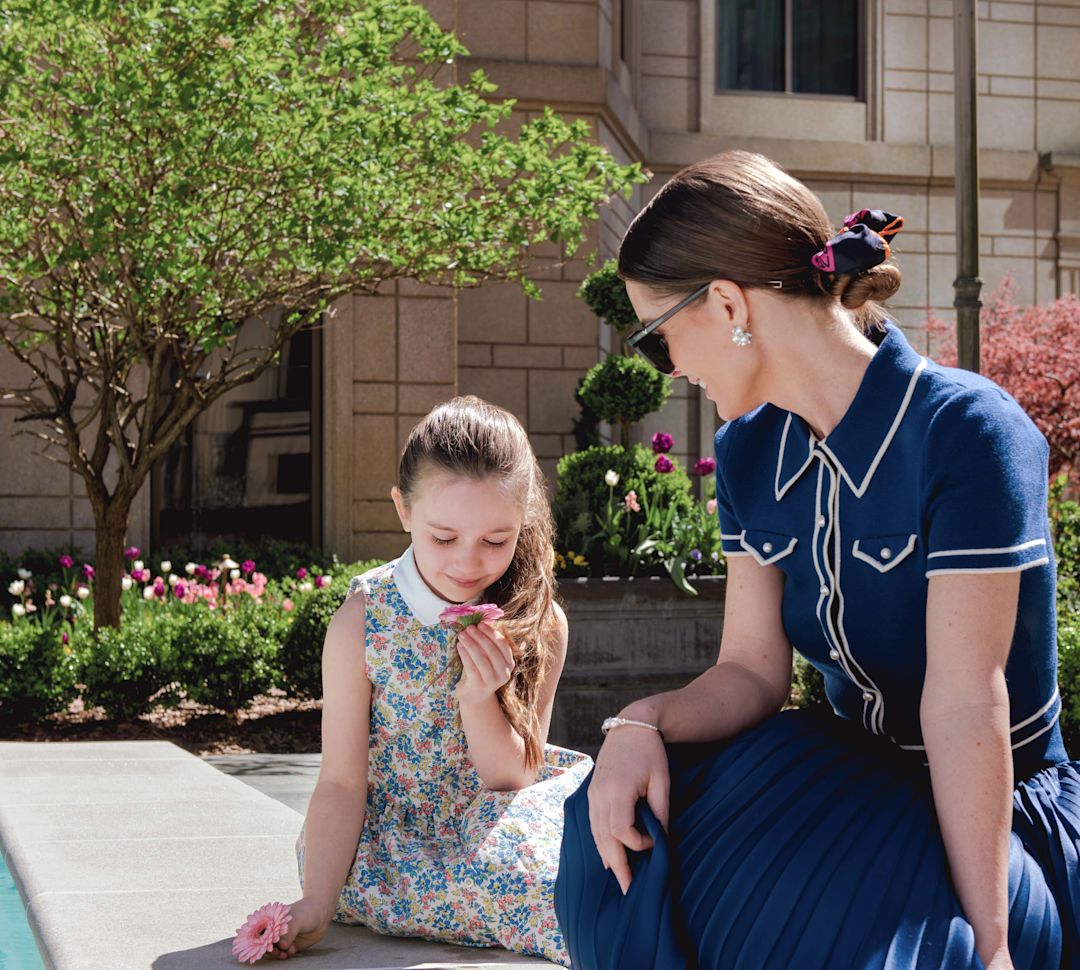 mother and daughter sitting in the courtyard looking at flowers